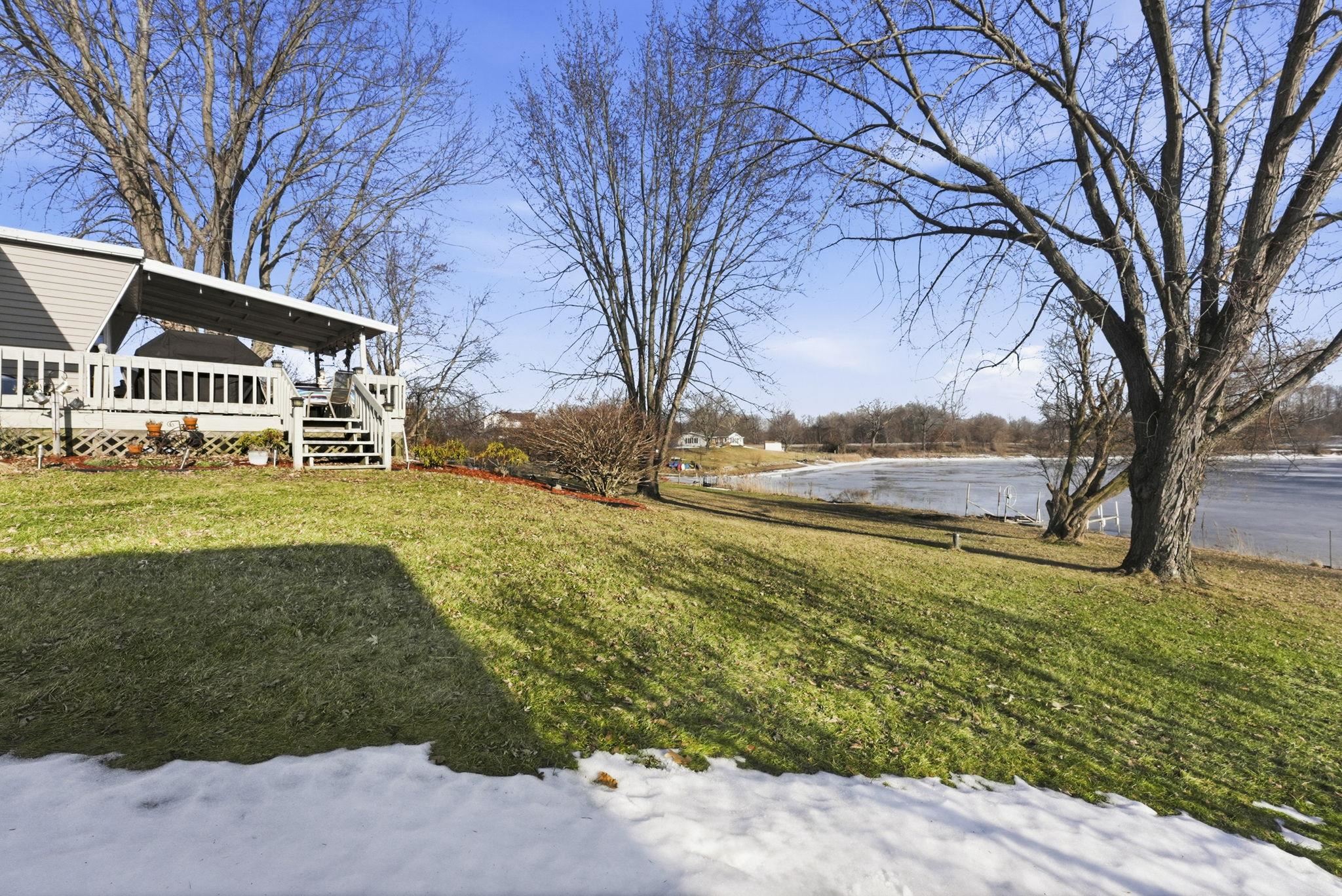 View of green lawn featuring a deck with water view