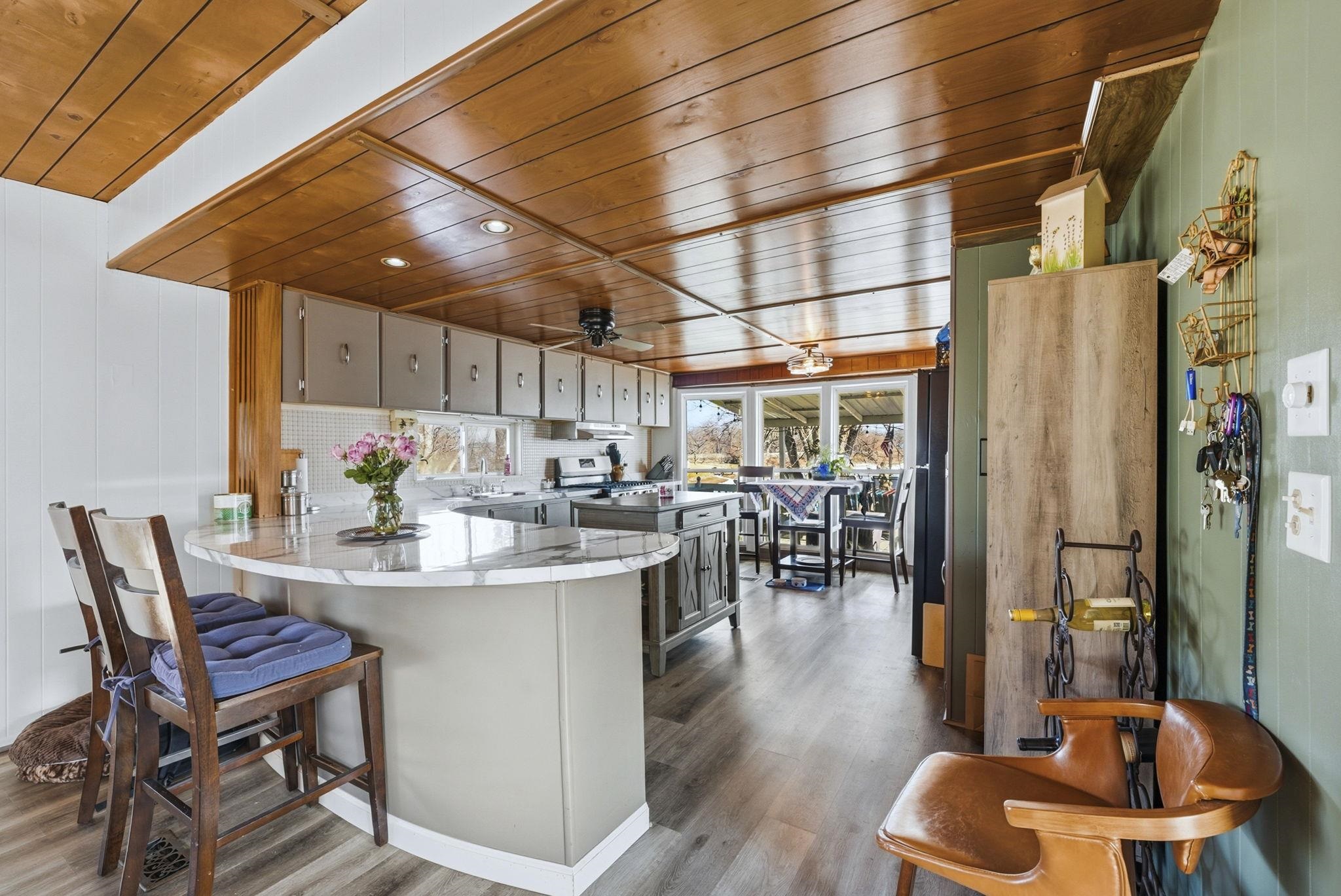 Kitchen with ceiling fan, wooden ceiling, a breakfast bar area, a peninsula, and stainless steel appliances