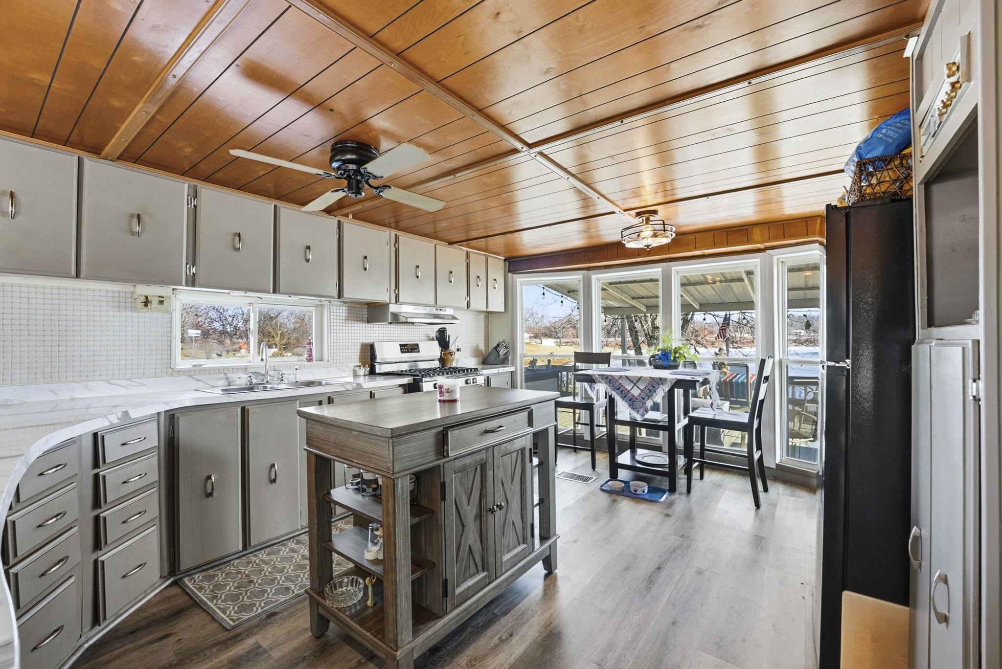 Kitchen featuring light countertops, wooden ceiling, stainless steel range with gas cooktop, backsplash, and freestanding refrigerator