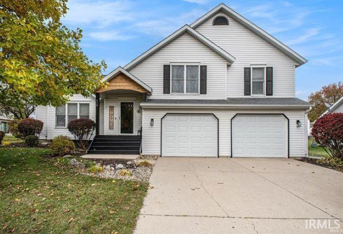 View of front of home with an attached garage, driveway, and a front lawn