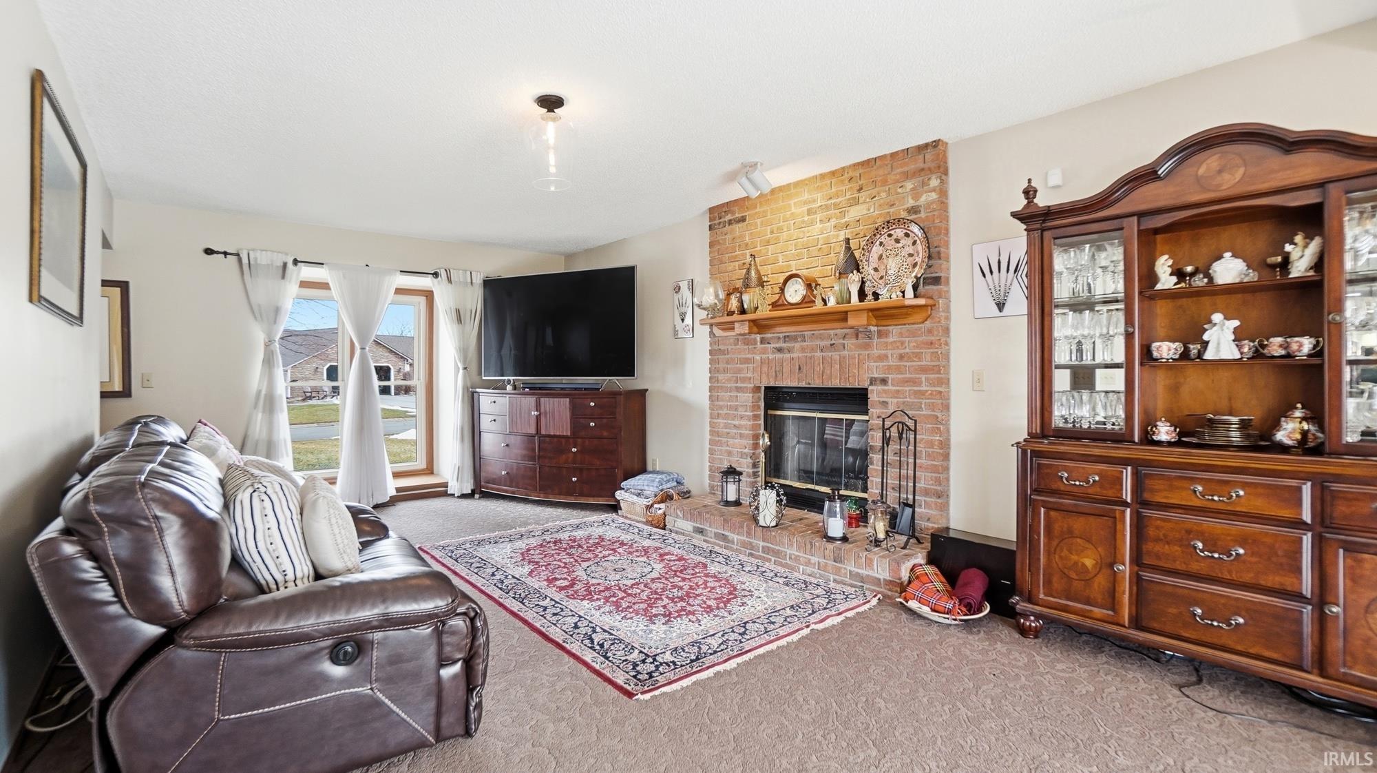 Carpeted living room with a brick fireplace