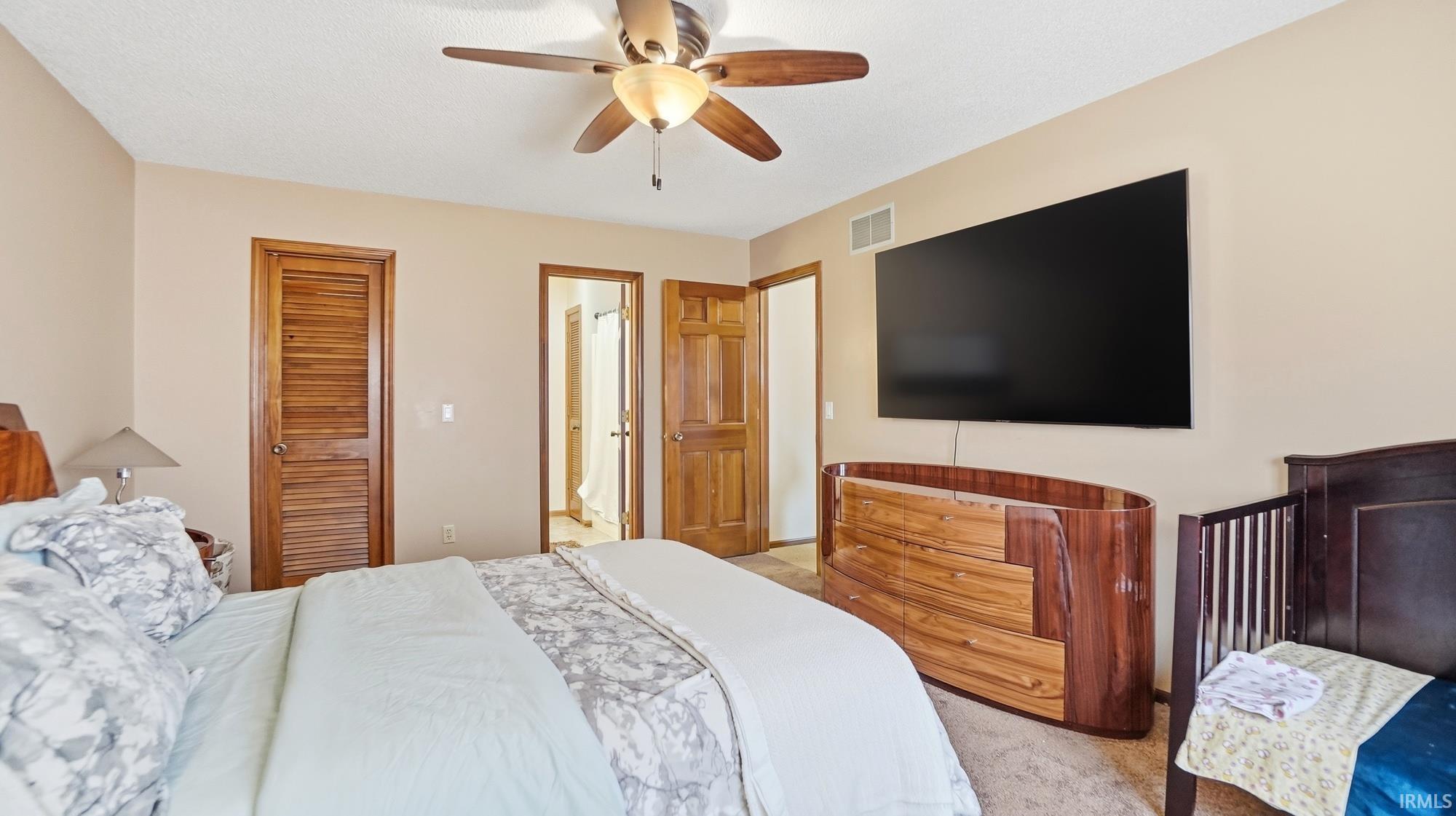 Bedroom with a ceiling fan, a closet, and light colored carpet