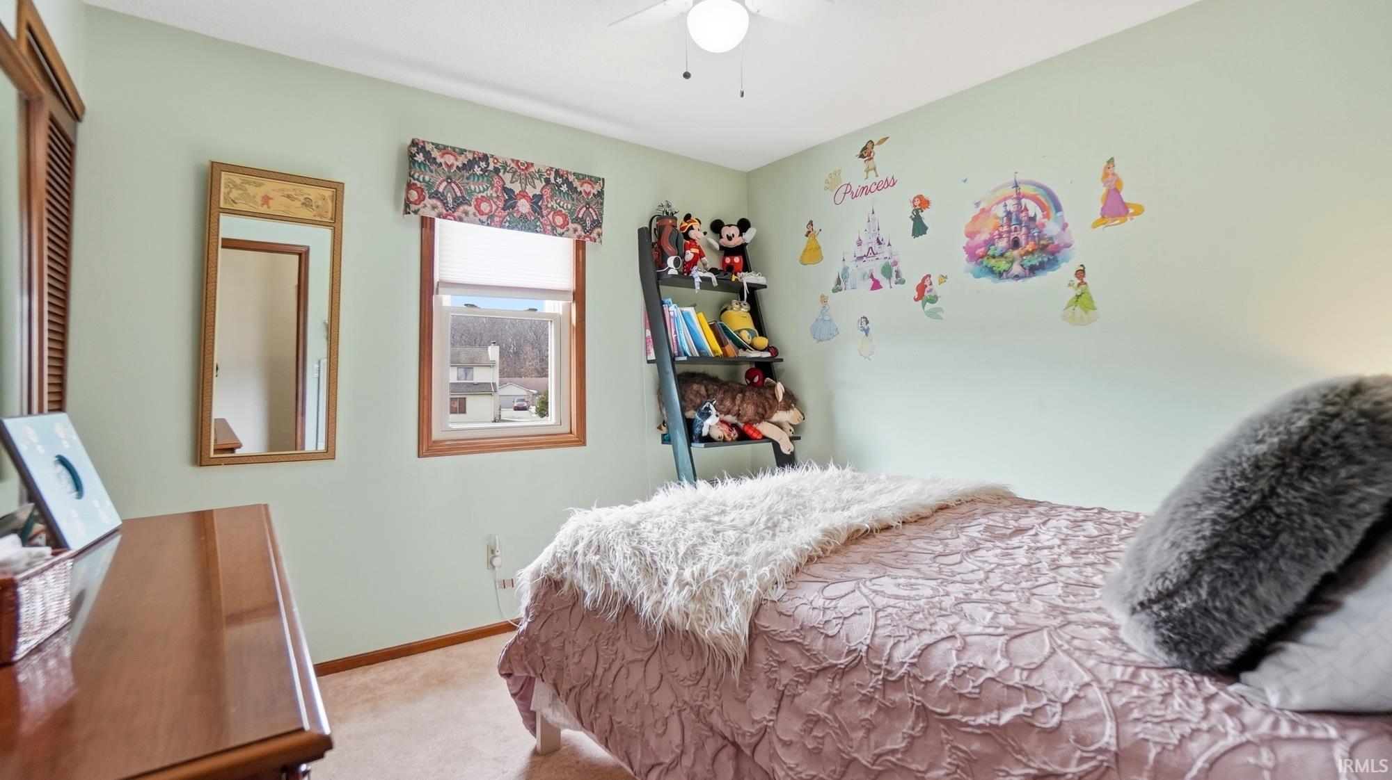 Carpeted bedroom with a ceiling fan and baseboards