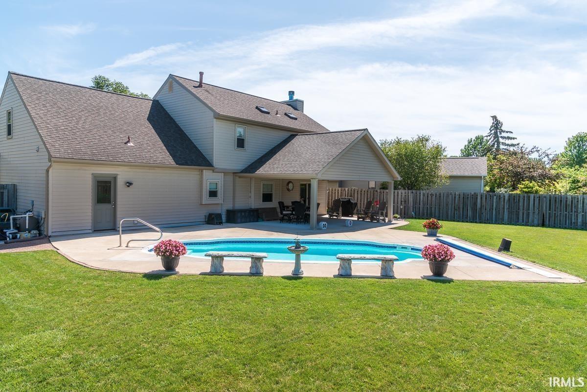 Back of property with a patio, roof with shingles, and a pool with connected hot tub
