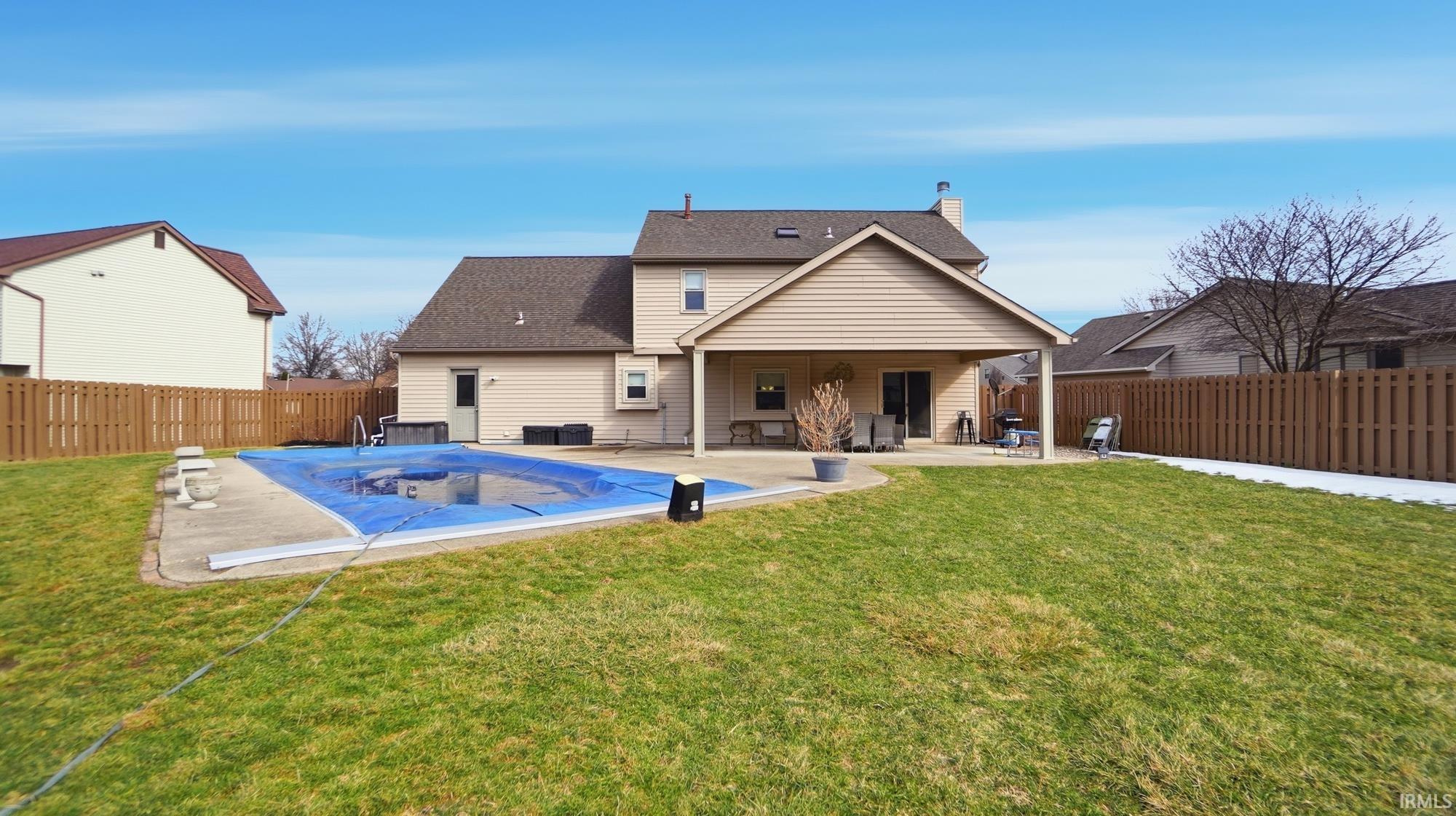 Rear view of property featuring a patio area, a chimney, a fenced backyard, and a shingled roof
