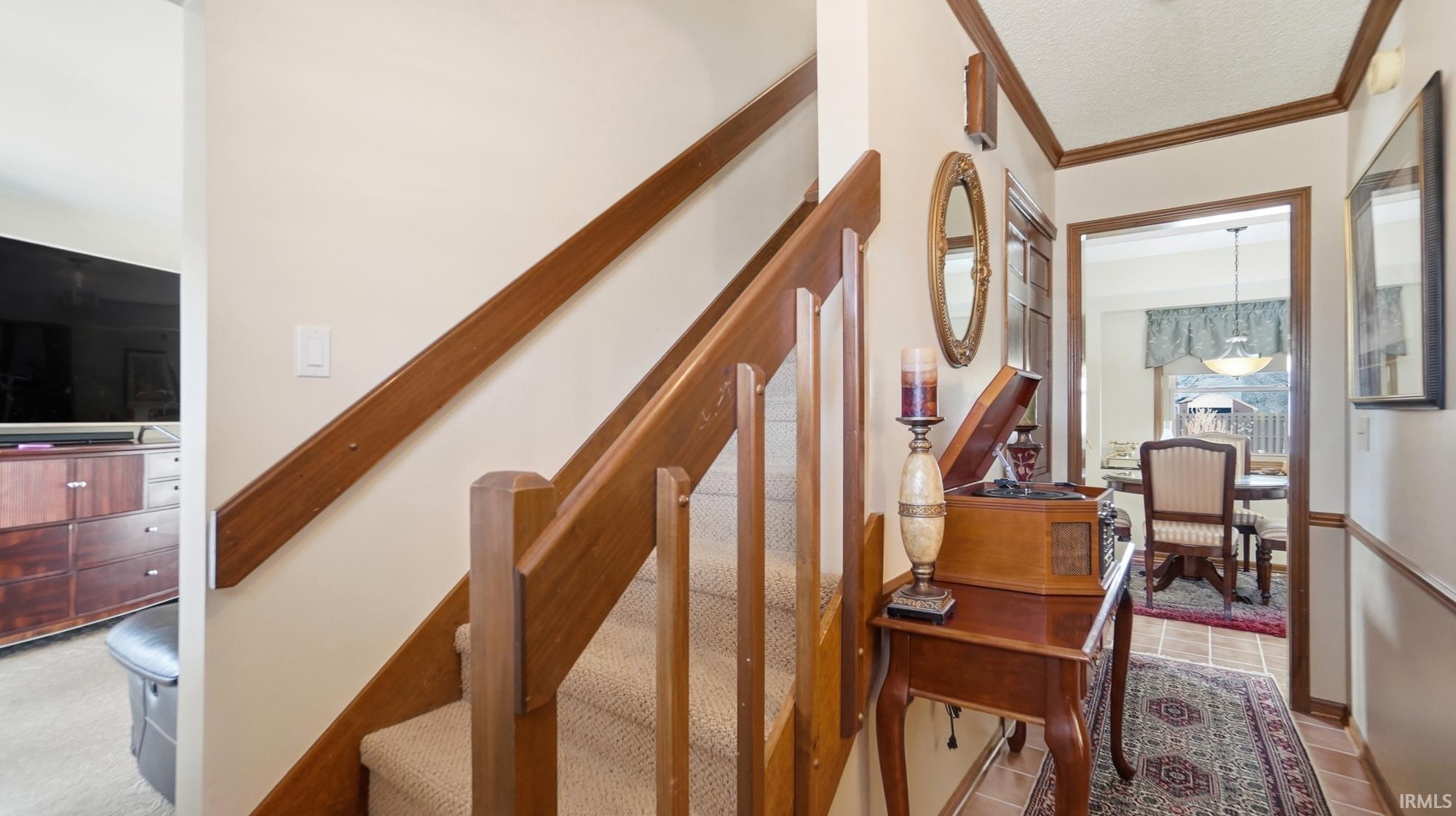 Staircase featuring ornamental molding, a textured ceiling, and tile patterned floors