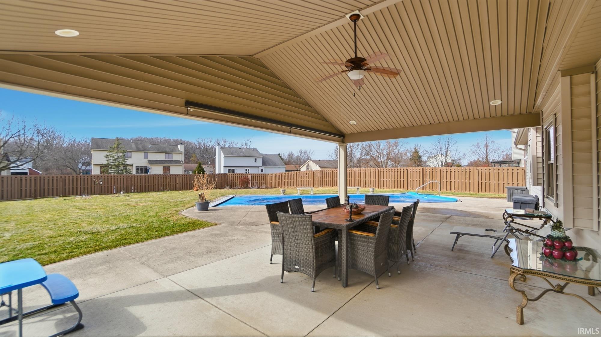 Fenced backyard with a ceiling fan, a patio, and outdoor dining area
