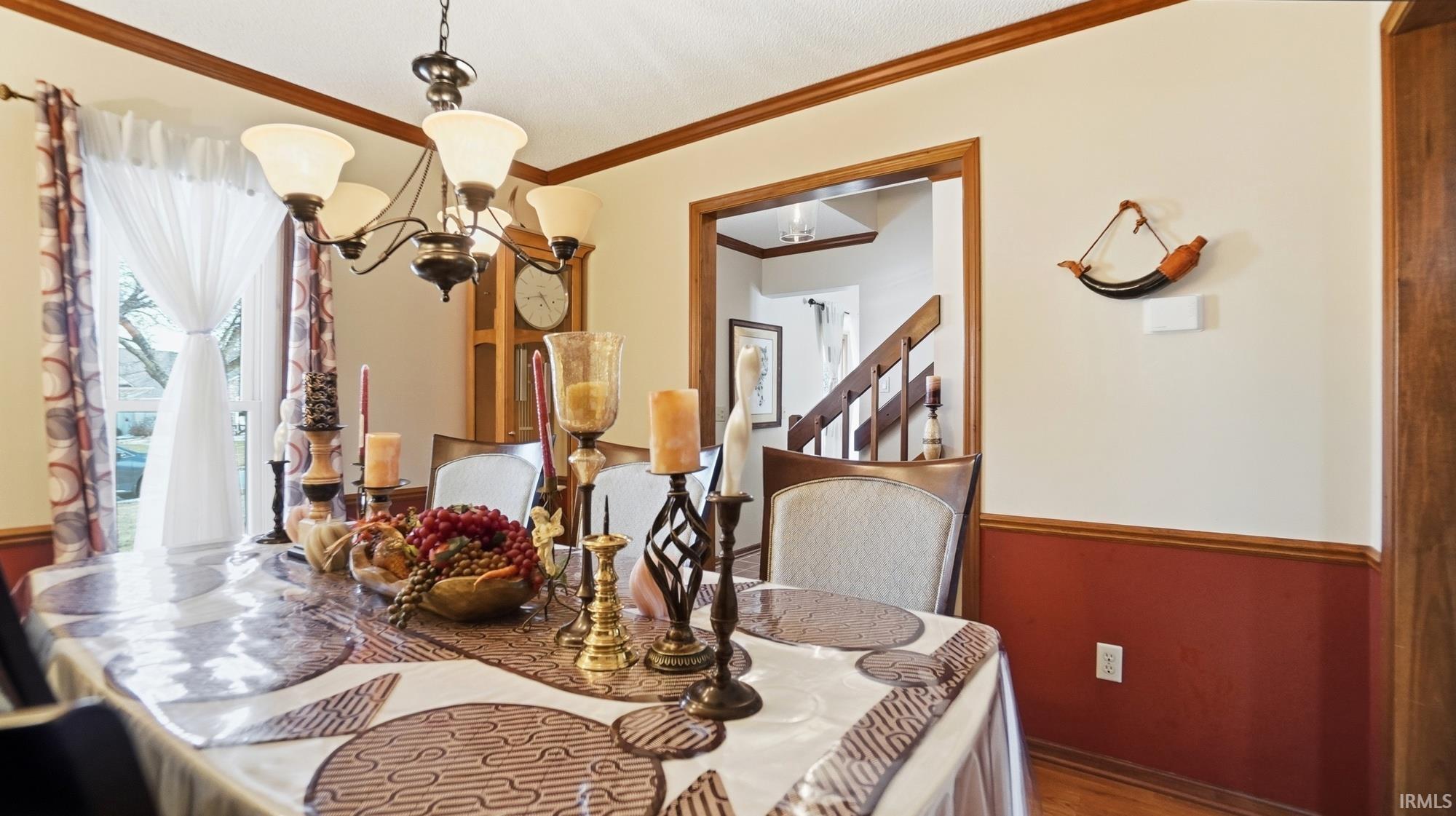 Dining space featuring hanging lights, crown molding, and wood finished floors