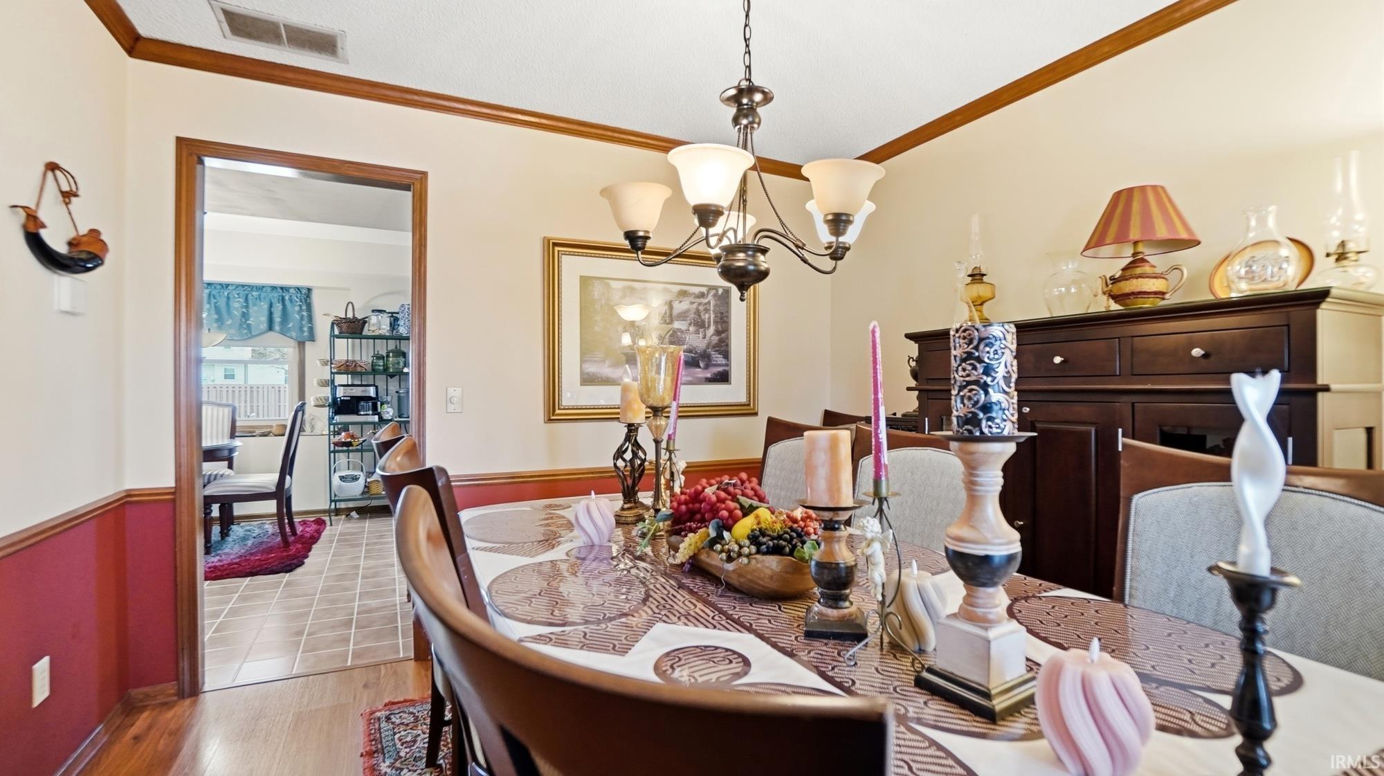 Tiled dining room with ornamental molding and suspended lighting