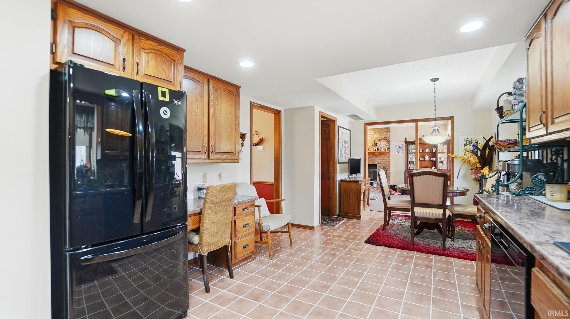 Kitchen with black appliances, pendant lighting, an office area, and wood finish cabinetry