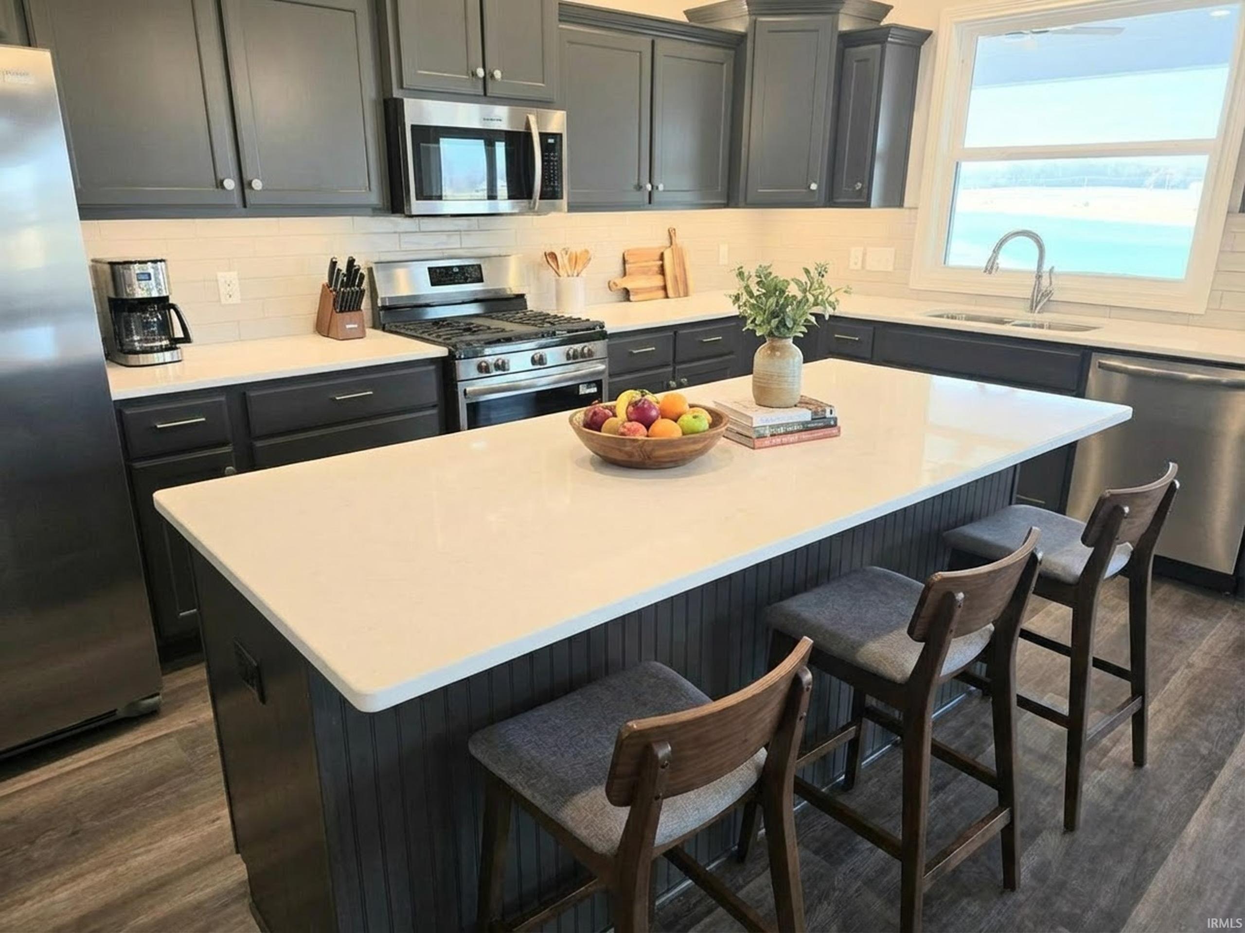 Kitchen featuring stainless steel appliances, tasteful backsplash, LVP floors, and a kitchen island