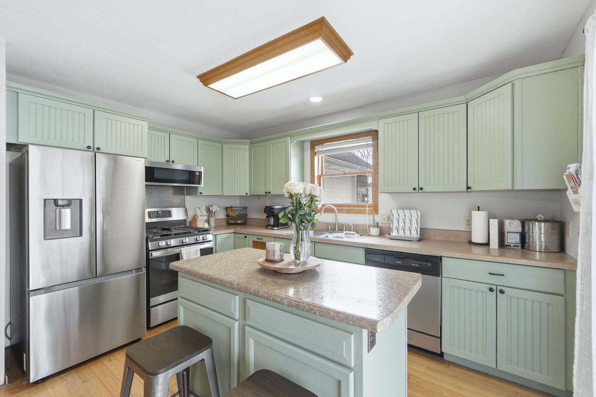 Kitchen featuring green cabinets, stainless steel appliances, a breakfast bar area, a kitchen island, and recessed lighting