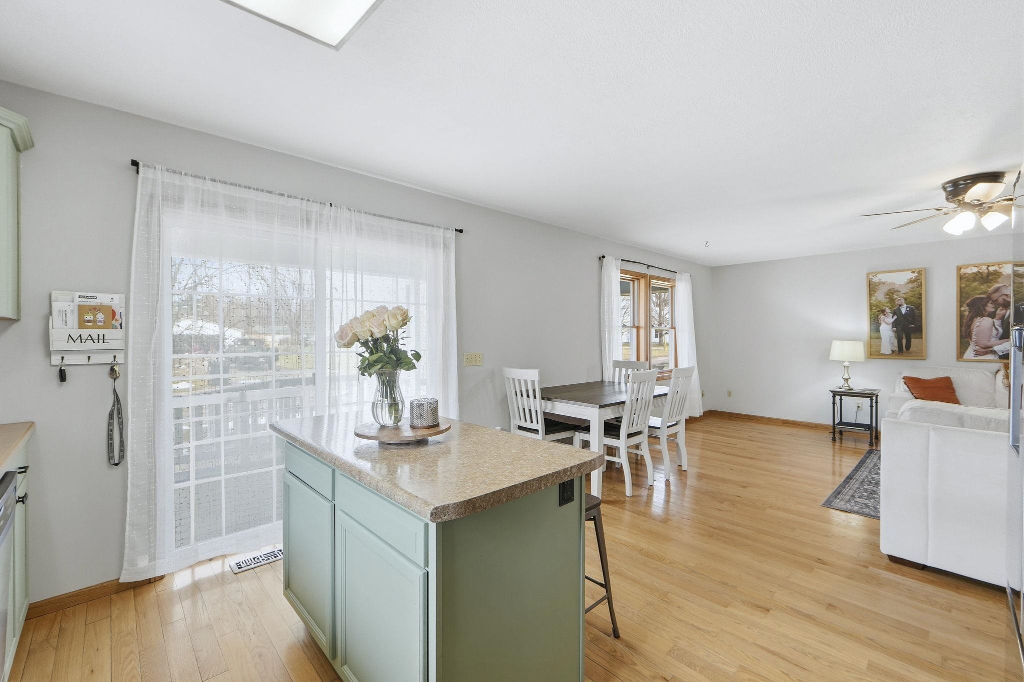 Kitchen with light wood-style flooring, a kitchen island, green cabinetry, a breakfast bar area, and a ceiling fan