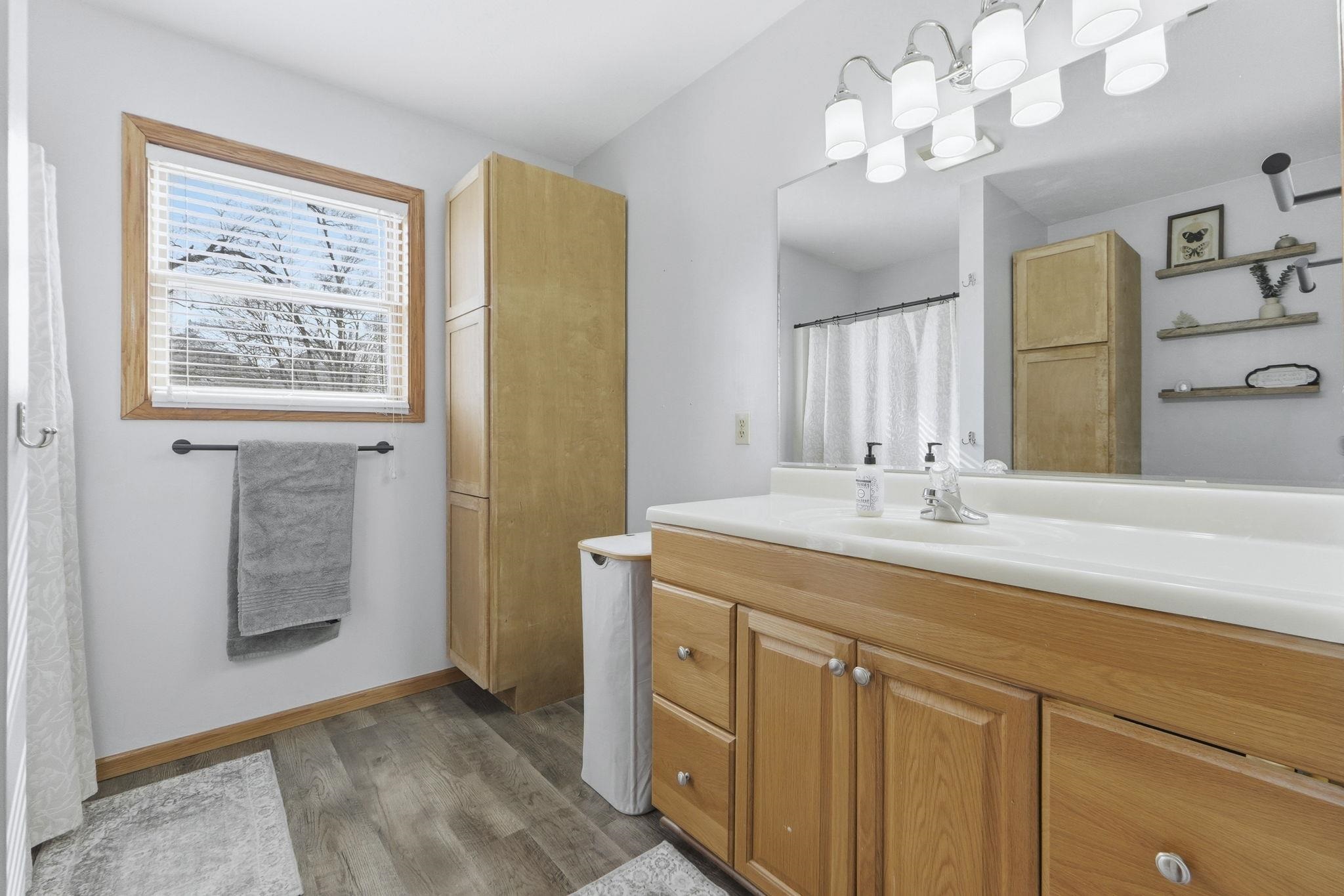 Bathroom with vanity, a shower with shower curtain, and dark wood-type flooring
