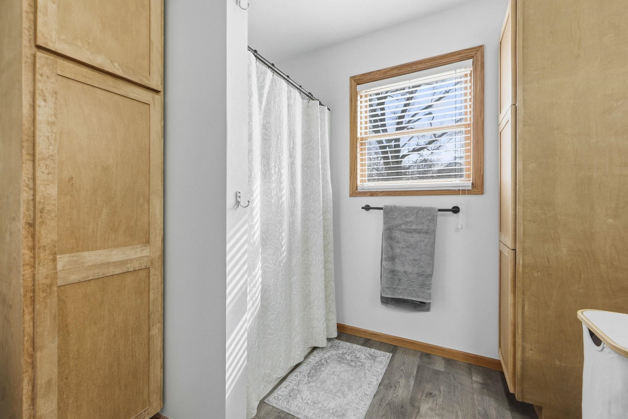 Bathroom with curtained shower and wood finished floors