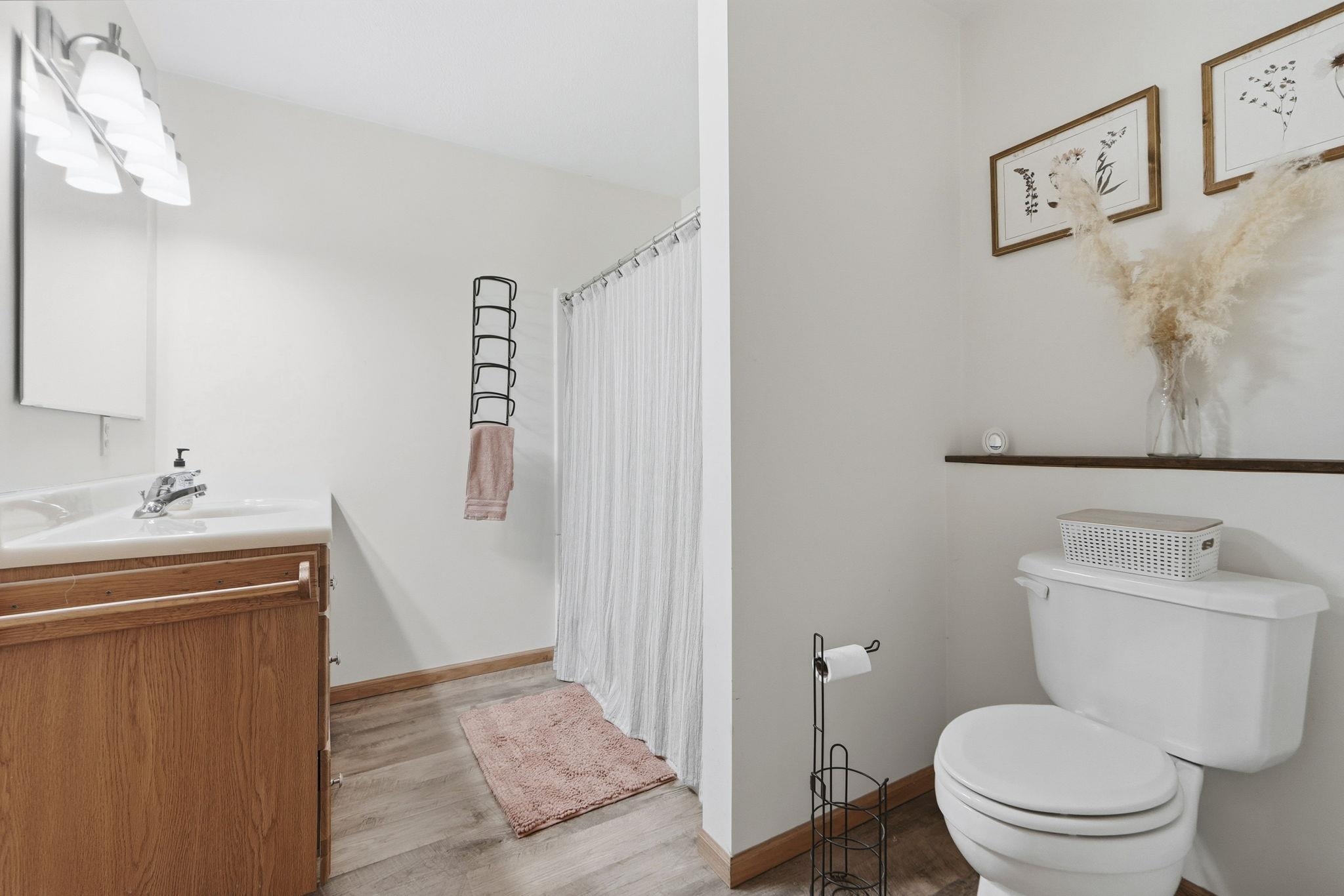Full bath with curtained shower, vanity, and light wood finished floors