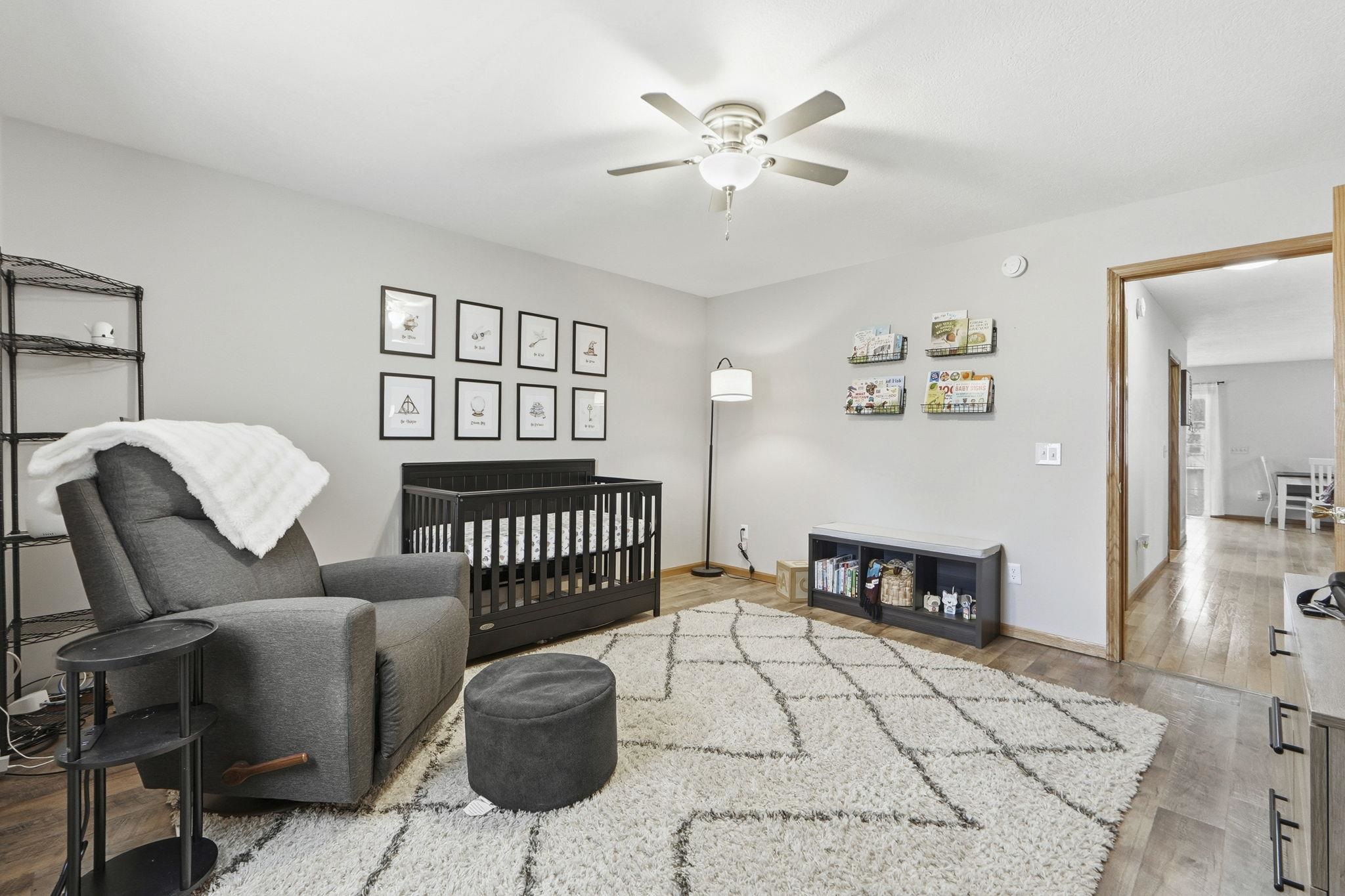 Bedroom featuring a nursery area, light wood-style floors, and ceiling fan