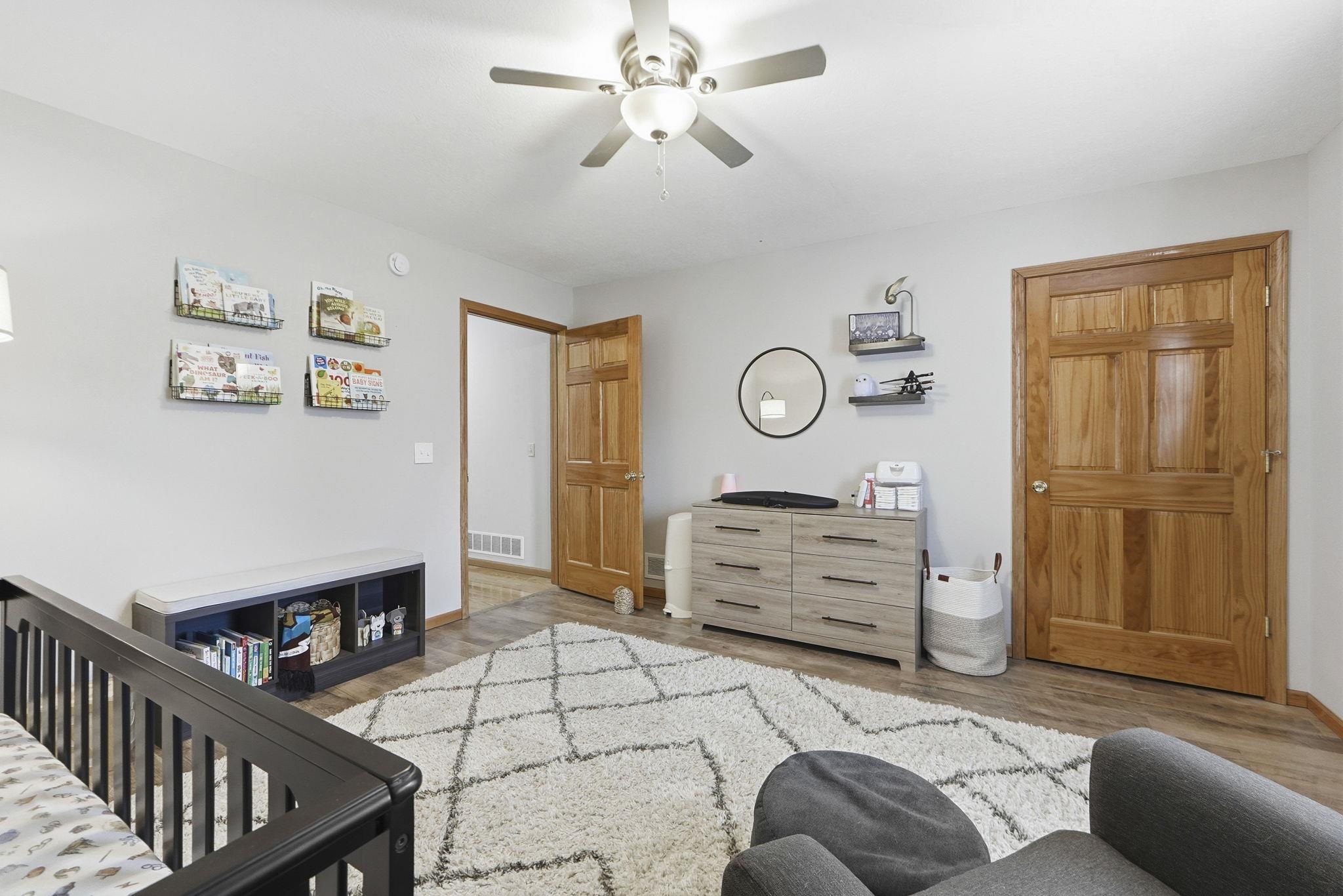 Bedroom with a crib, light wood-type flooring, and a ceiling fan