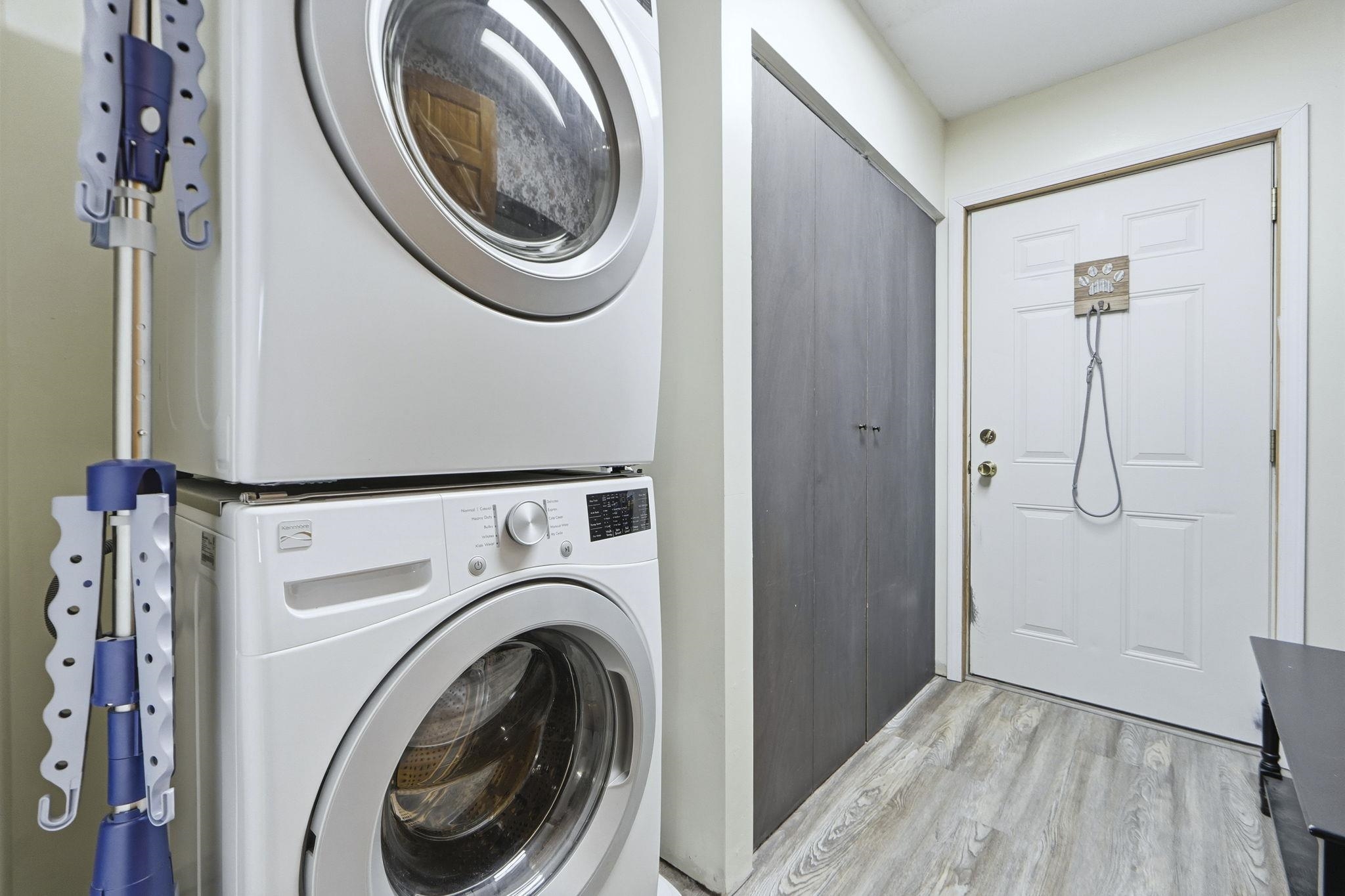 Laundry room featuring light wood-type flooring and stacked washer / drying machine