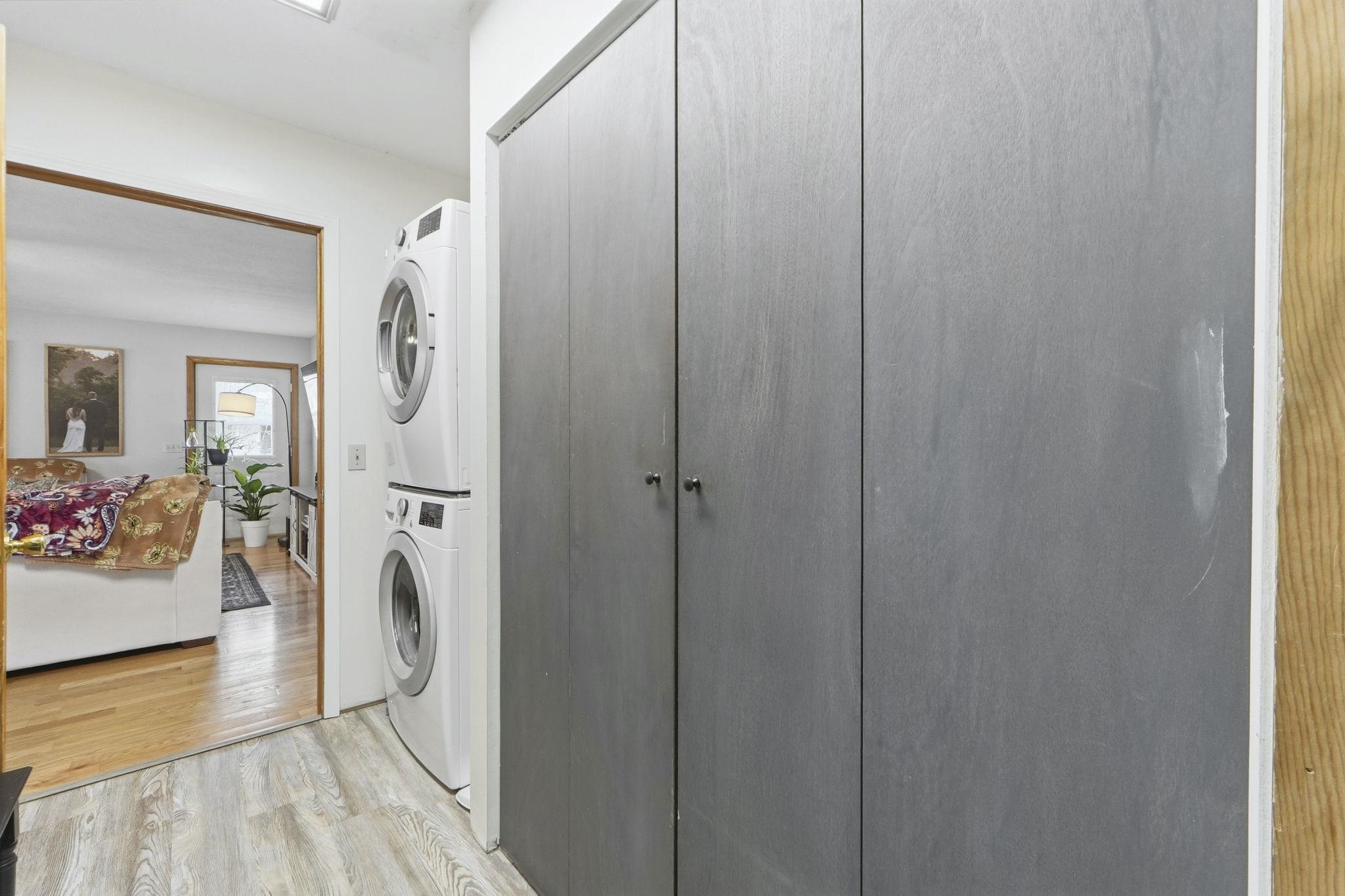Laundry area with light wood finished floors and stacked washer / drying machine