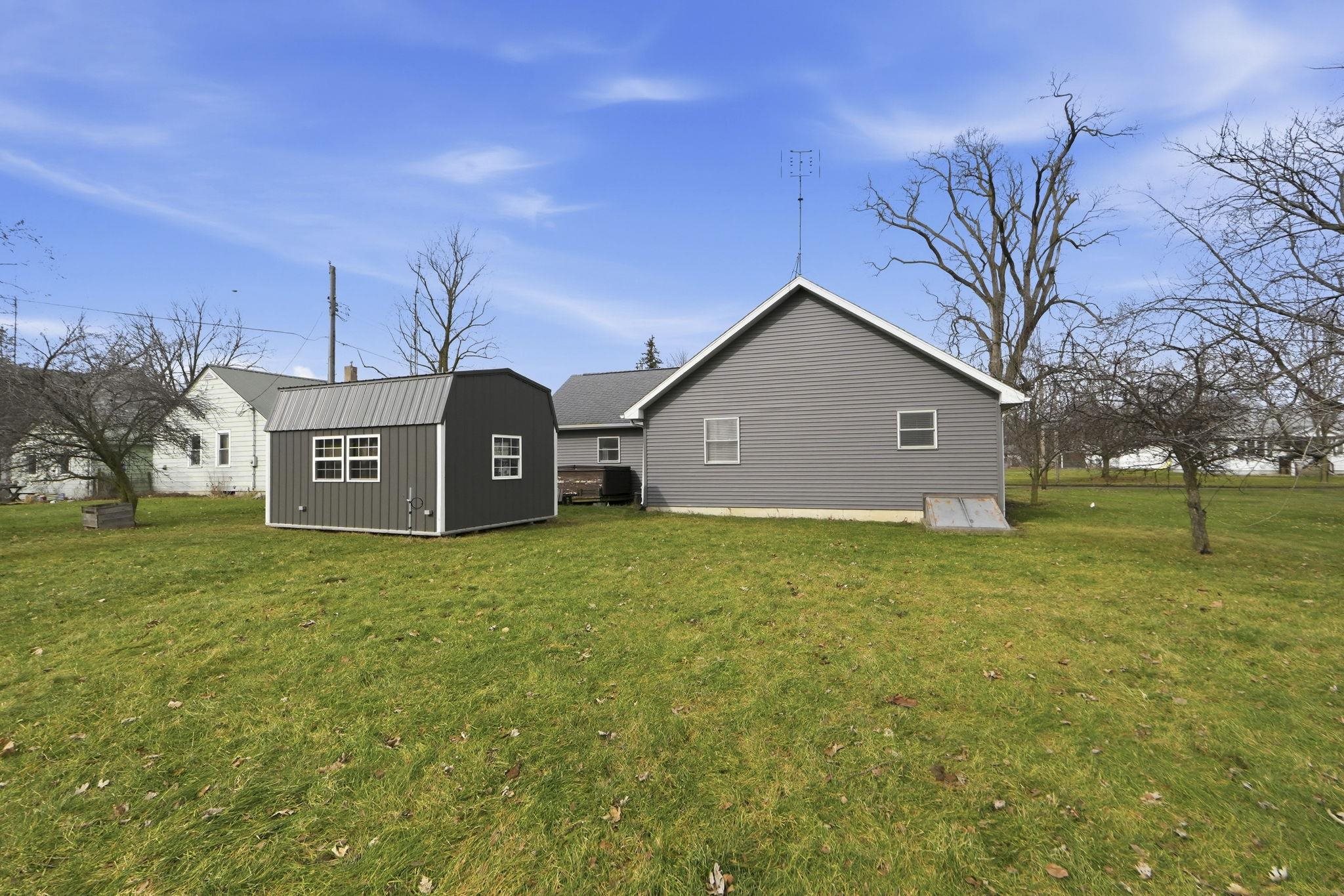 Back of property with a shed and a lawn