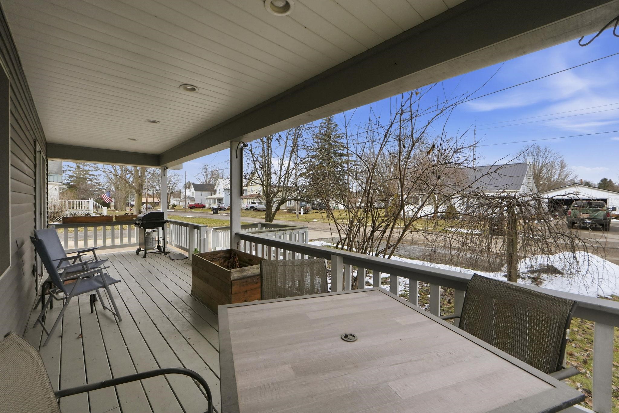 Porch featuring a grill, outdoor dining area, and a residential view