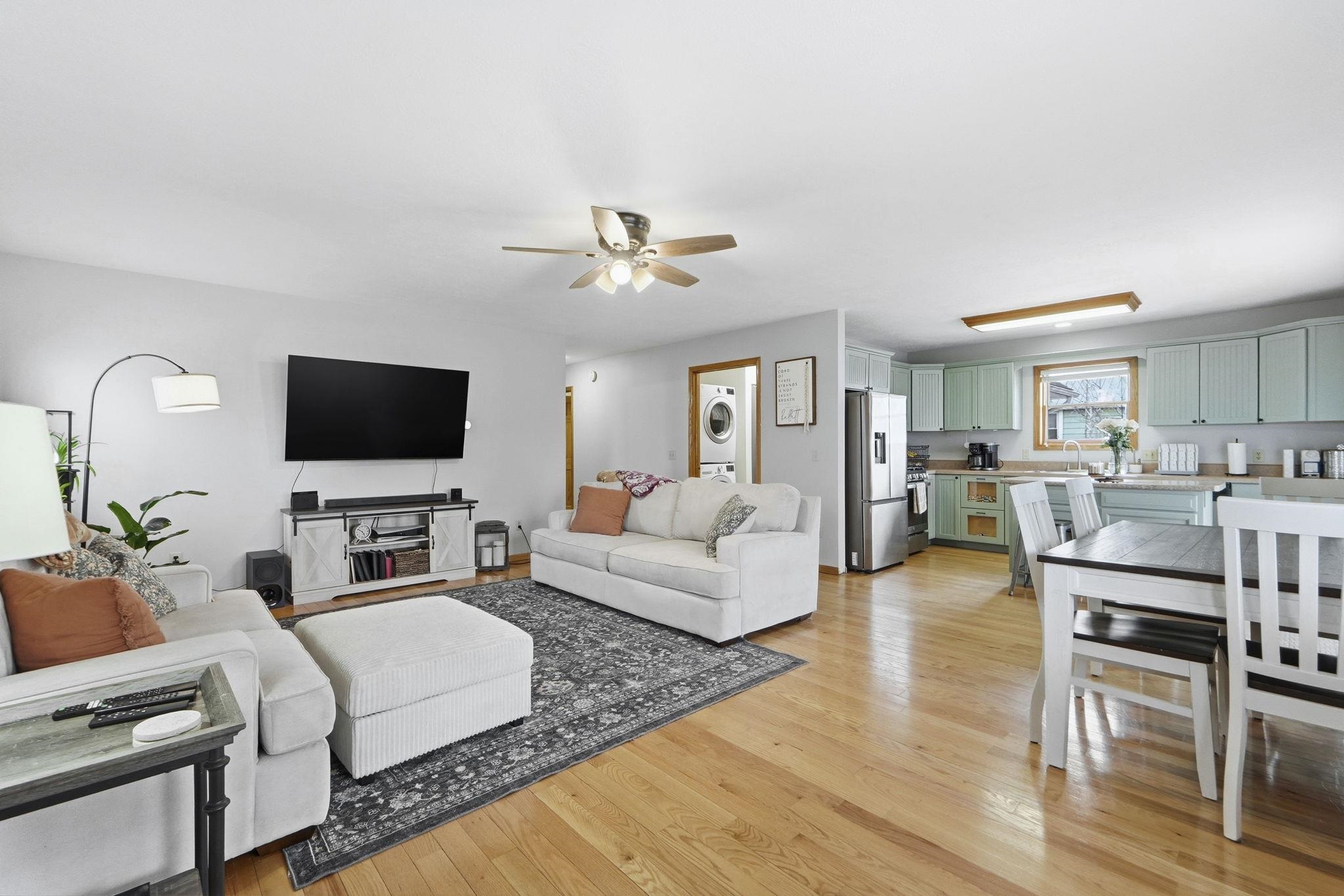 Living area featuring light wood-style floors, stacked washer / drying machine, and ceiling fan