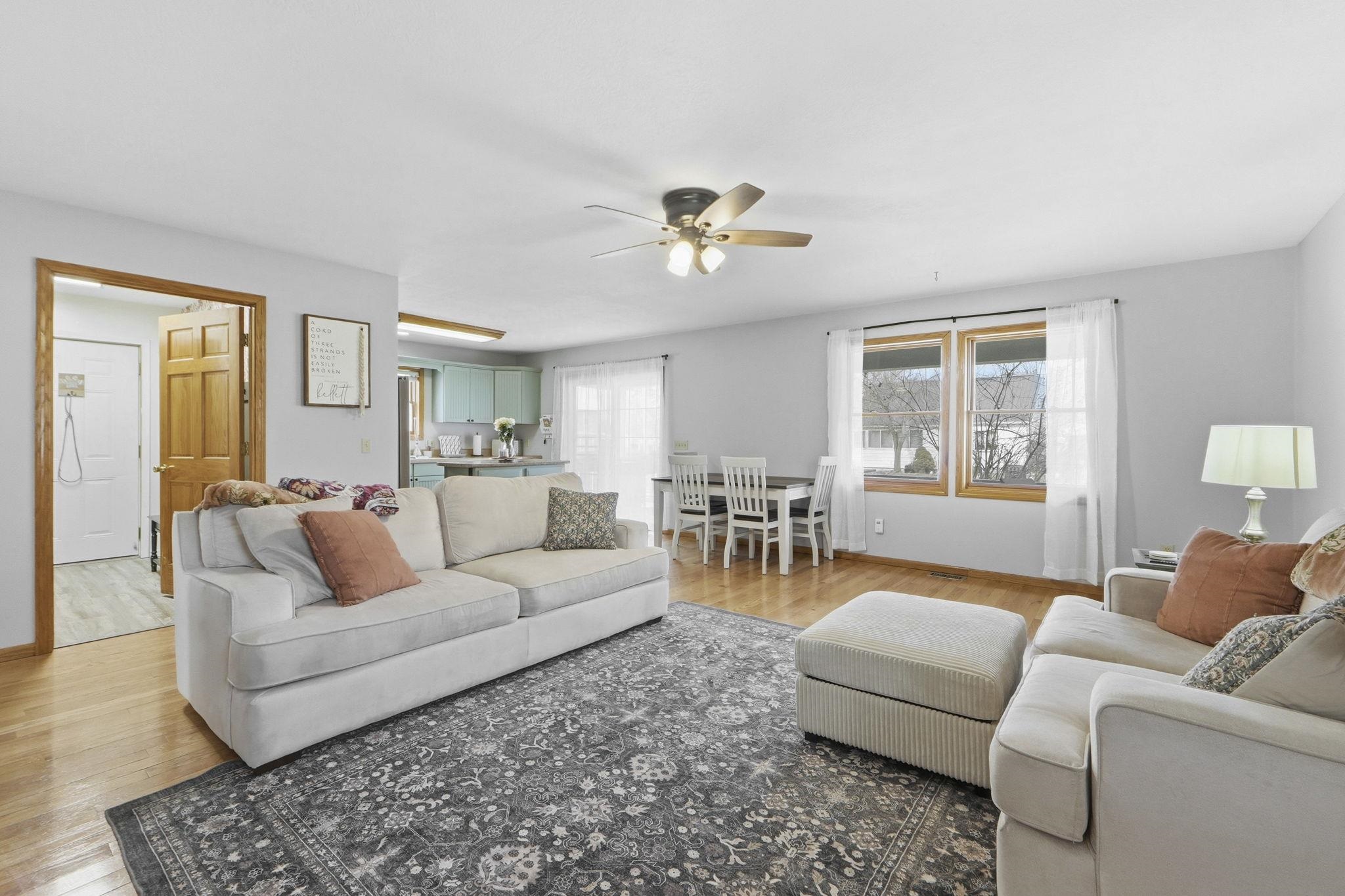 Living room with a ceiling fan, healthy amount of natural light, and light wood-style flooring