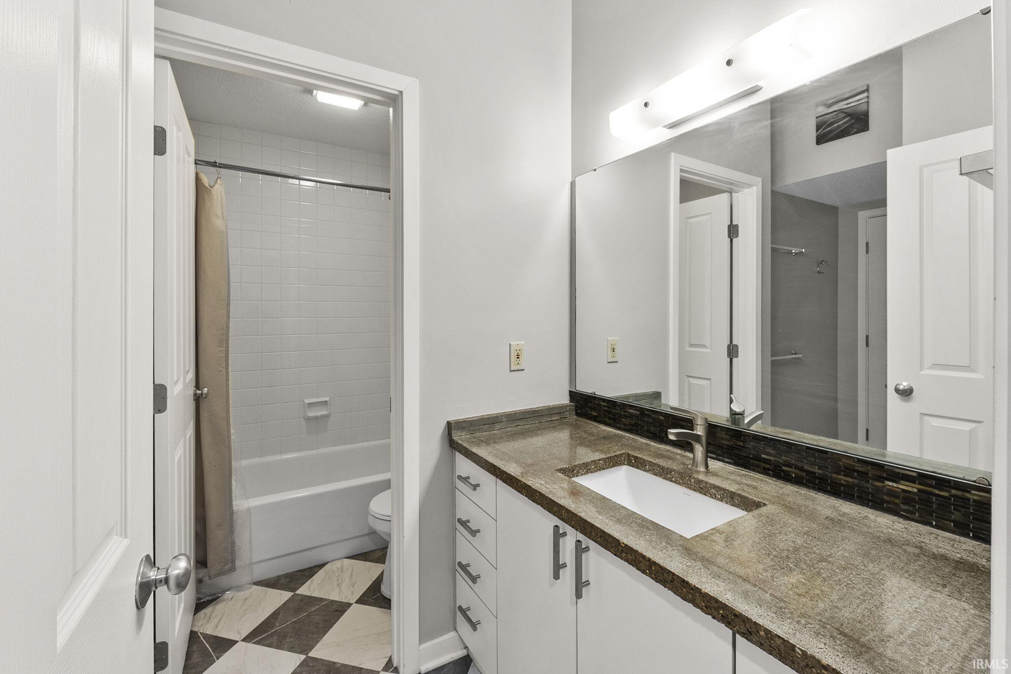 Bathroom featuring vanity, shower / bath combo, and dark floors