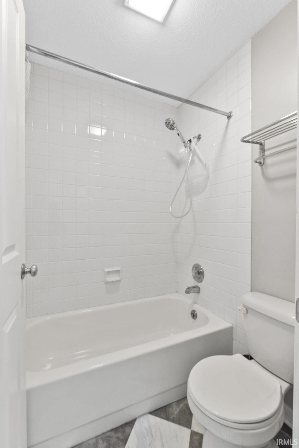 Bathroom with bathtub / shower combination and a textured ceiling