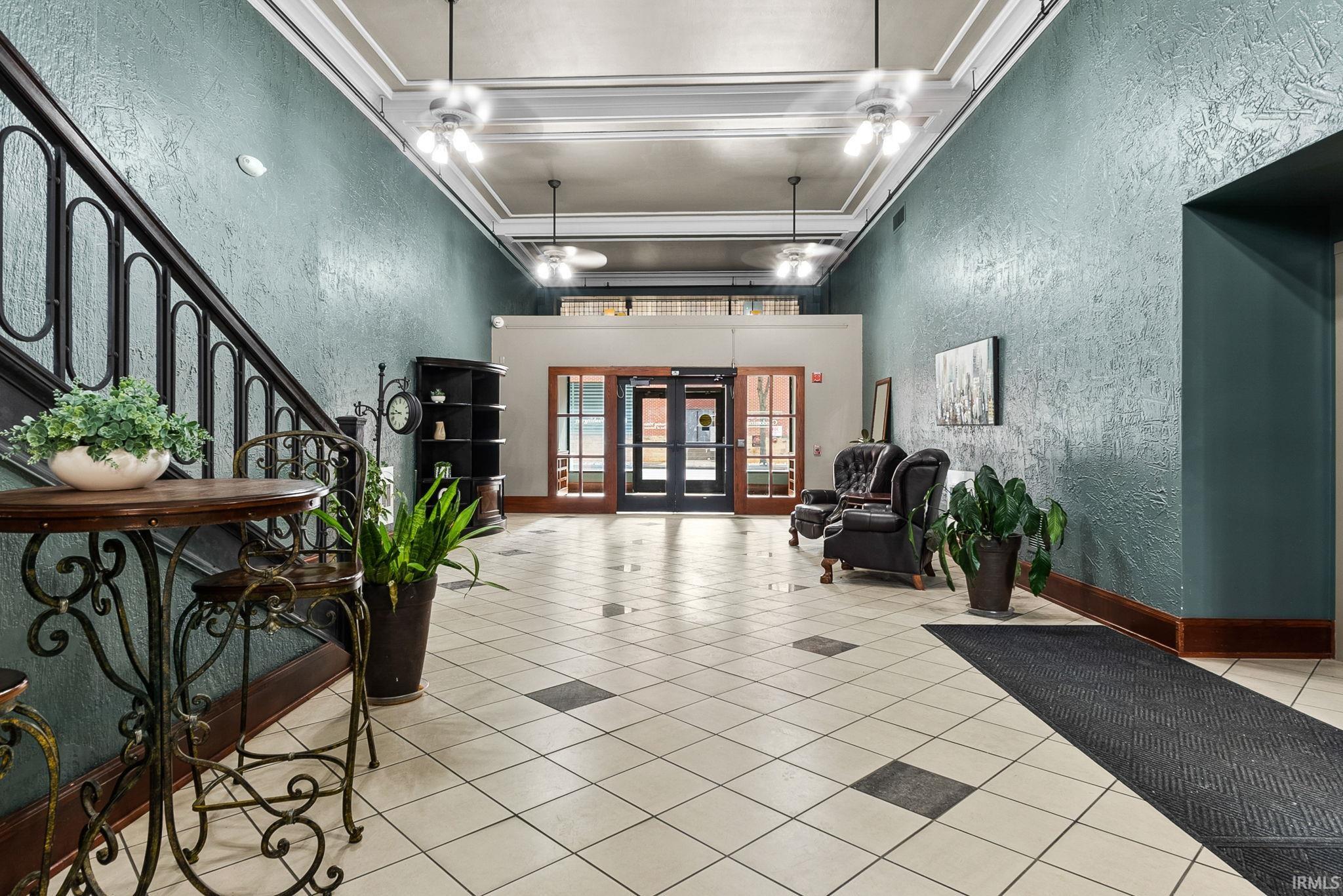 Community lobby with a textured wall, a high ceiling, and ornamental molding