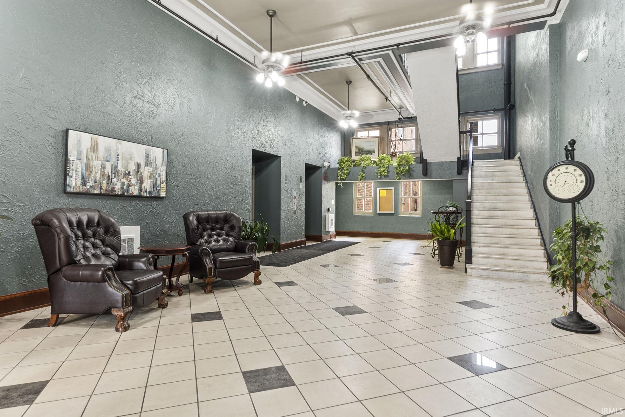 Community lobby with a textured wall, a high ceiling, and crown molding