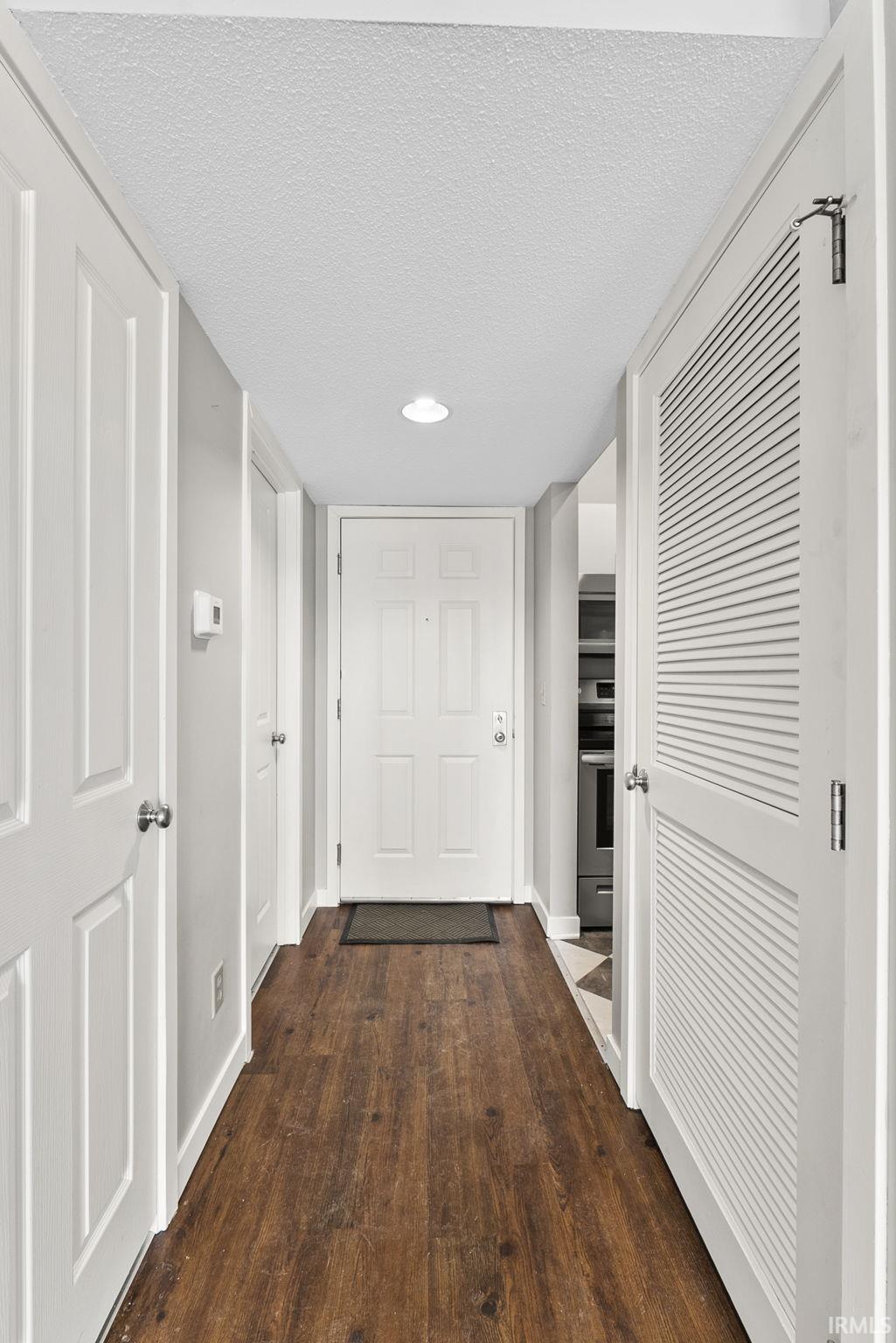 Corridor with dark wood-style floors, a textured ceiling, and recessed lighting