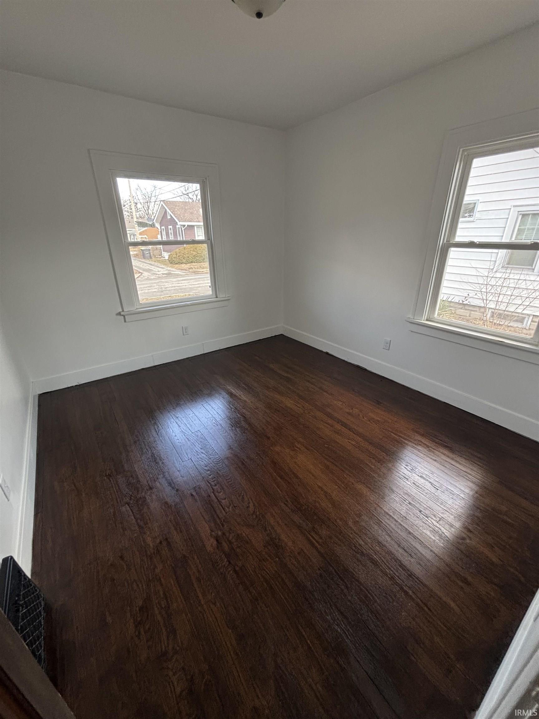 Spare room with baseboards and dark wood-type flooring