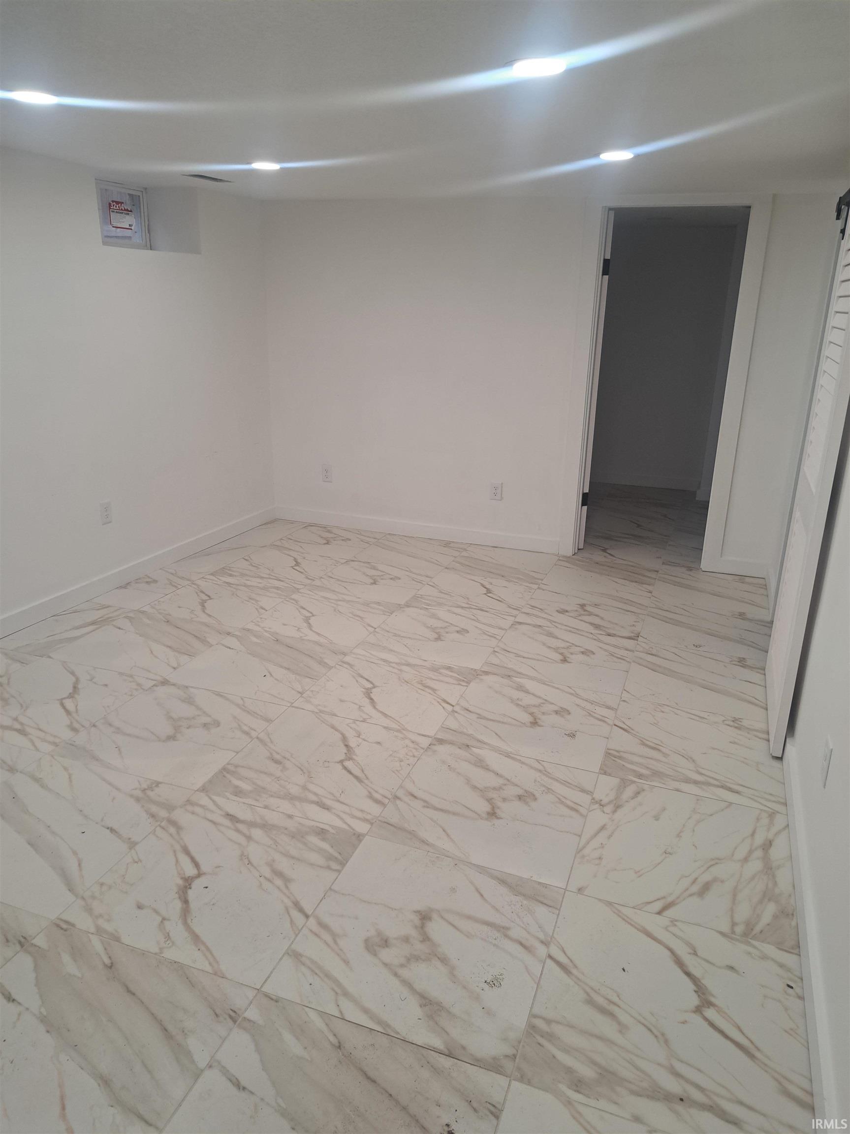 Finished basement with light marble finish flooring and baseboards