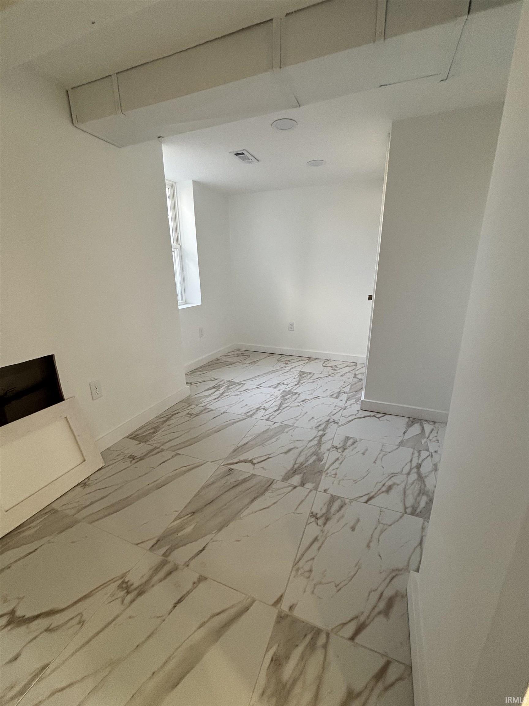 Empty room featuring light marble finish floors and baseboards