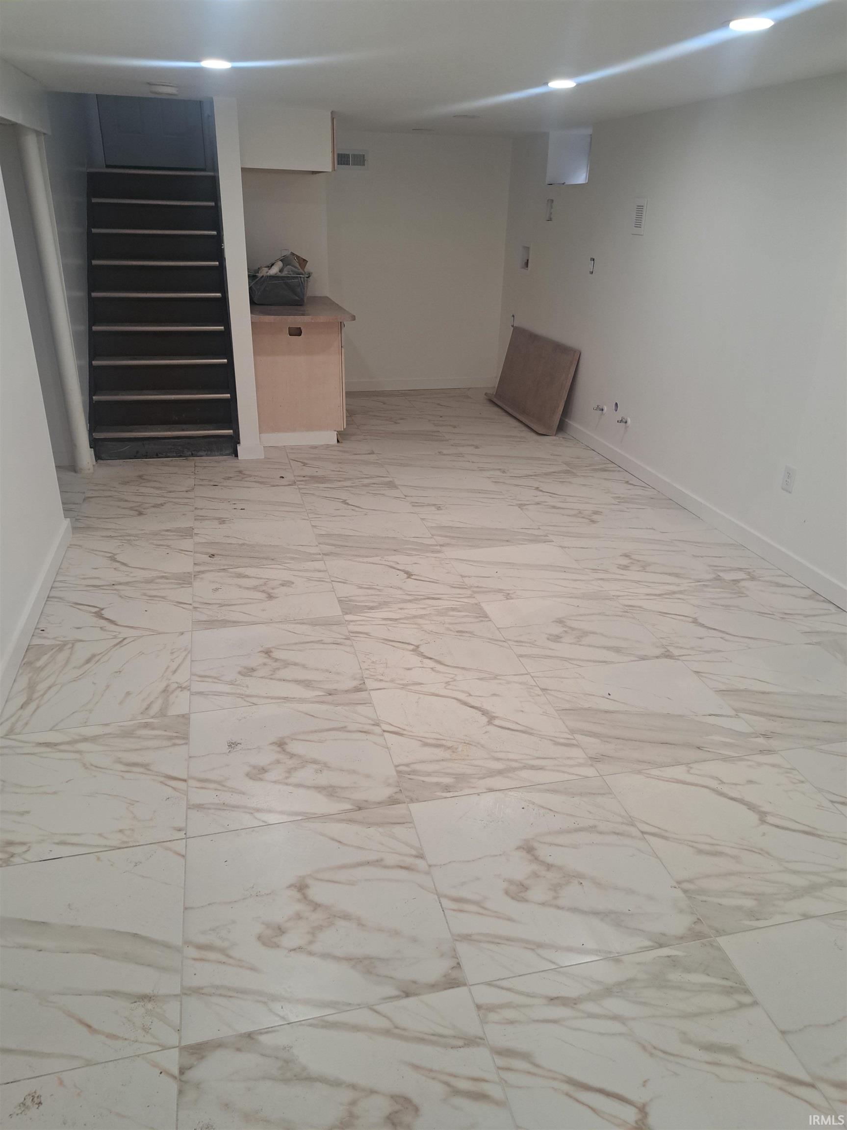 Finished below grade area featuring light marble finish flooring and baseboards