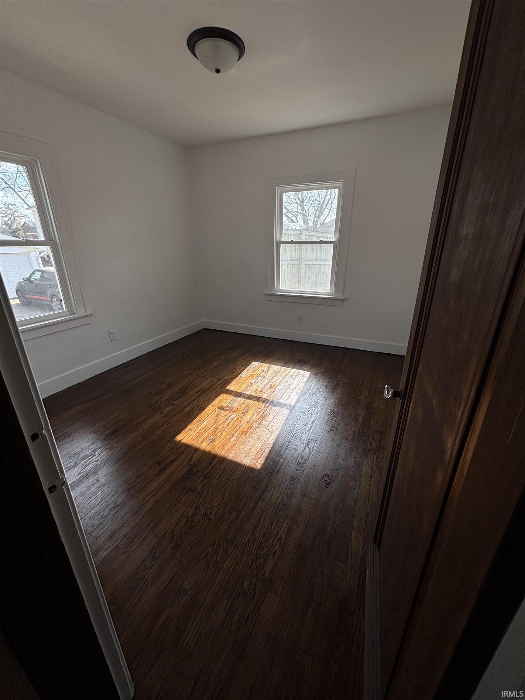 Unfurnished bedroom featuring baseboards and dark wood finished floors