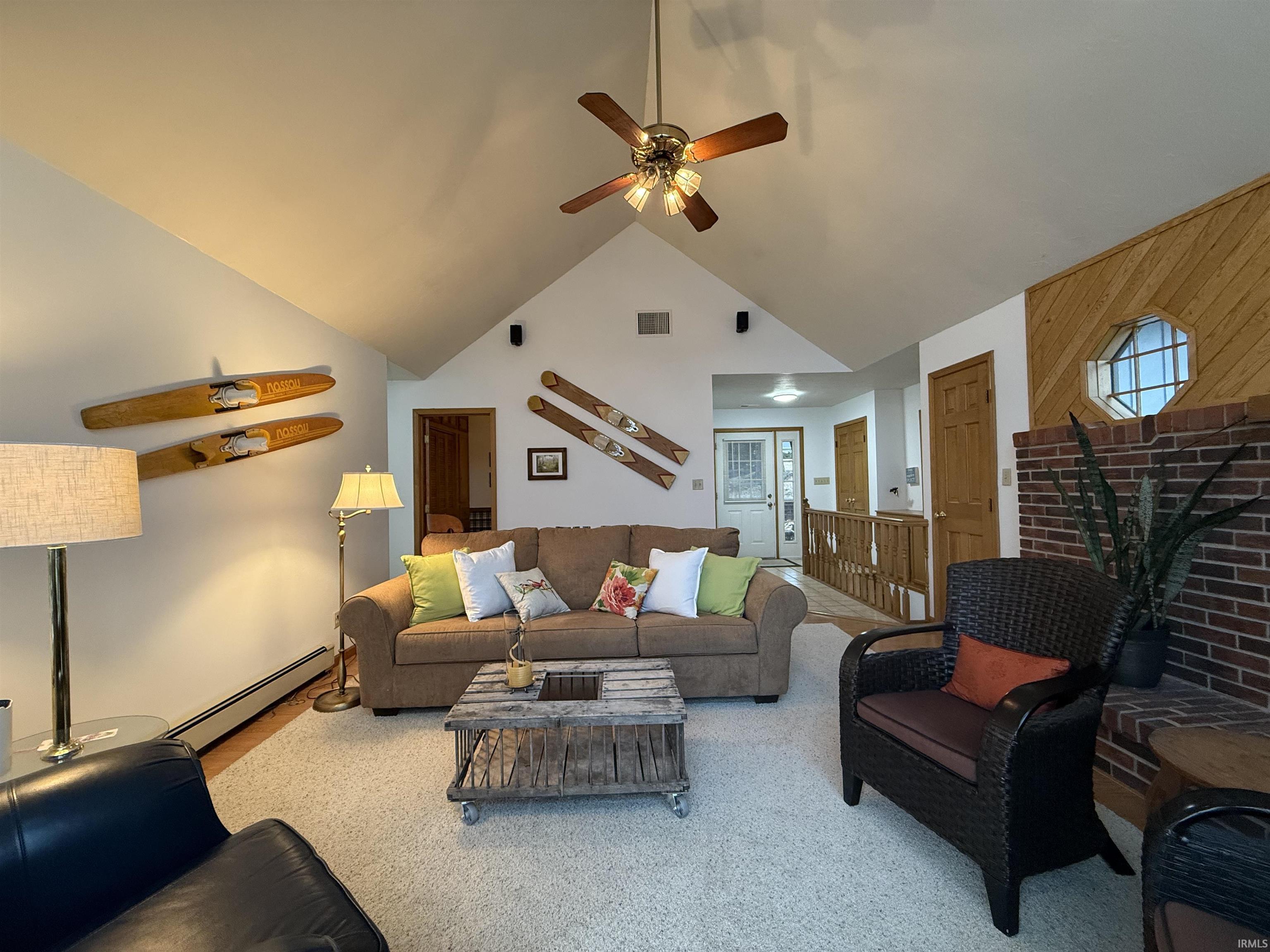 Living area featuring a baseboard heating unit, ceiling fan, and vaulted ceiling