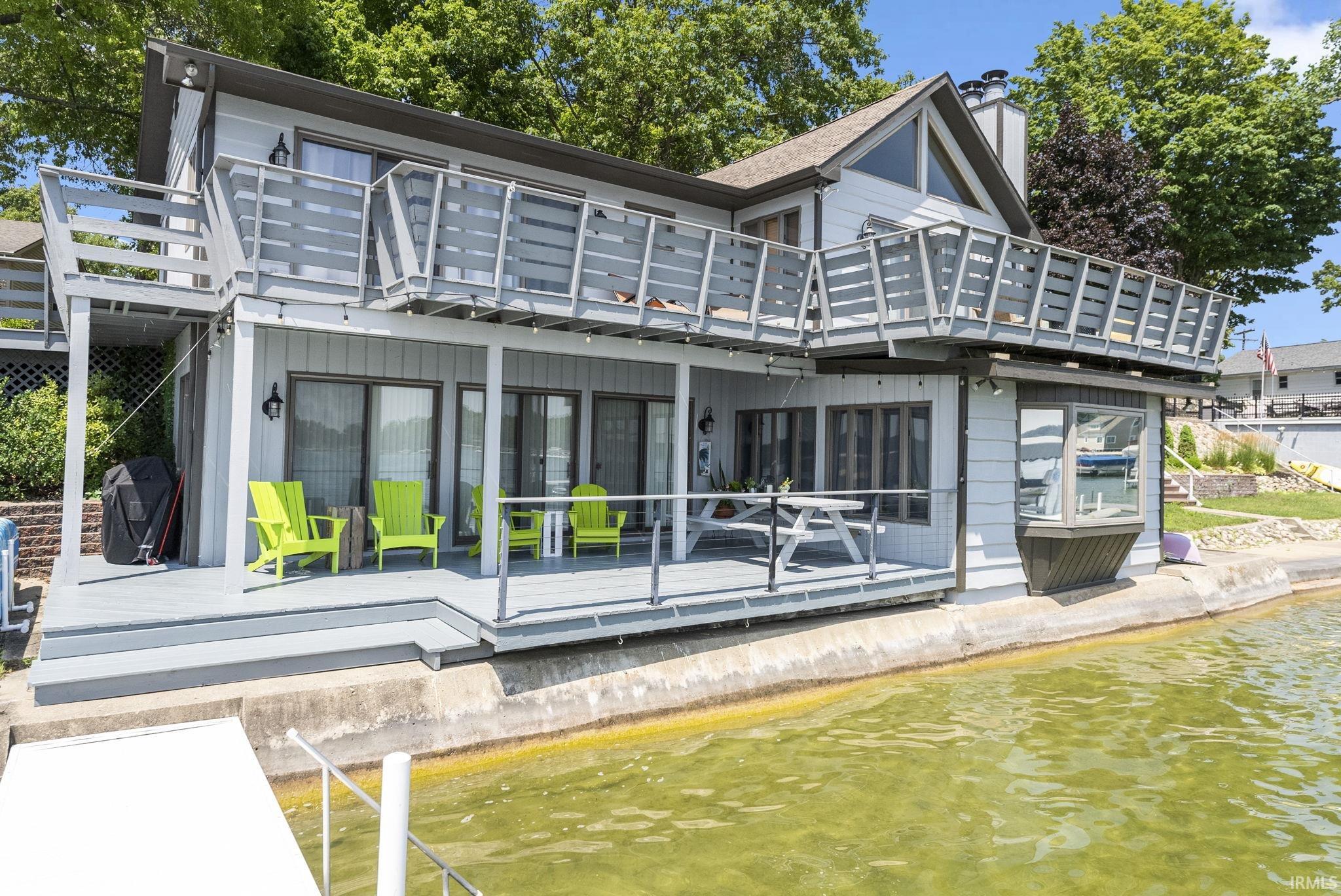 Rear view of house with a patio area, a chimney, and a deck with water view