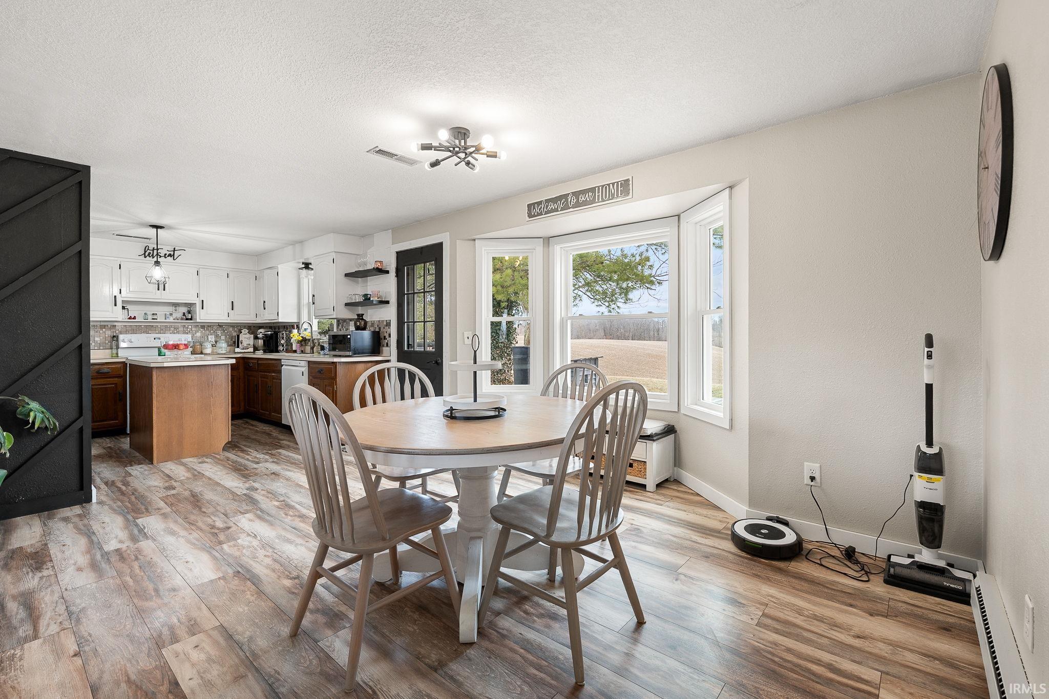 Dining area with light wood finished floors, a baseboard radiator, and a textured ceiling