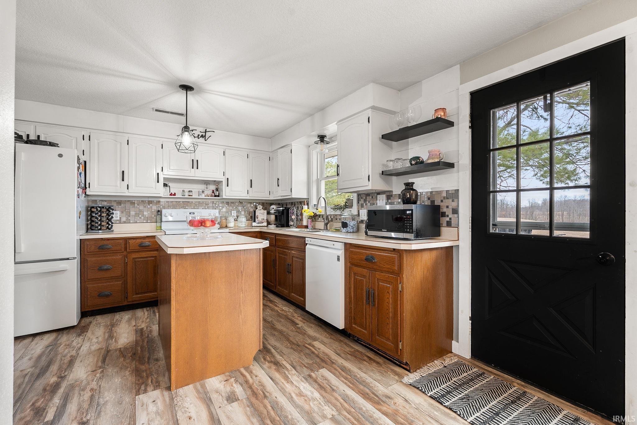 Kitchen featuring open shelves, light countertops, dual tone cabinetry, white appliances, and light wood-style flooring