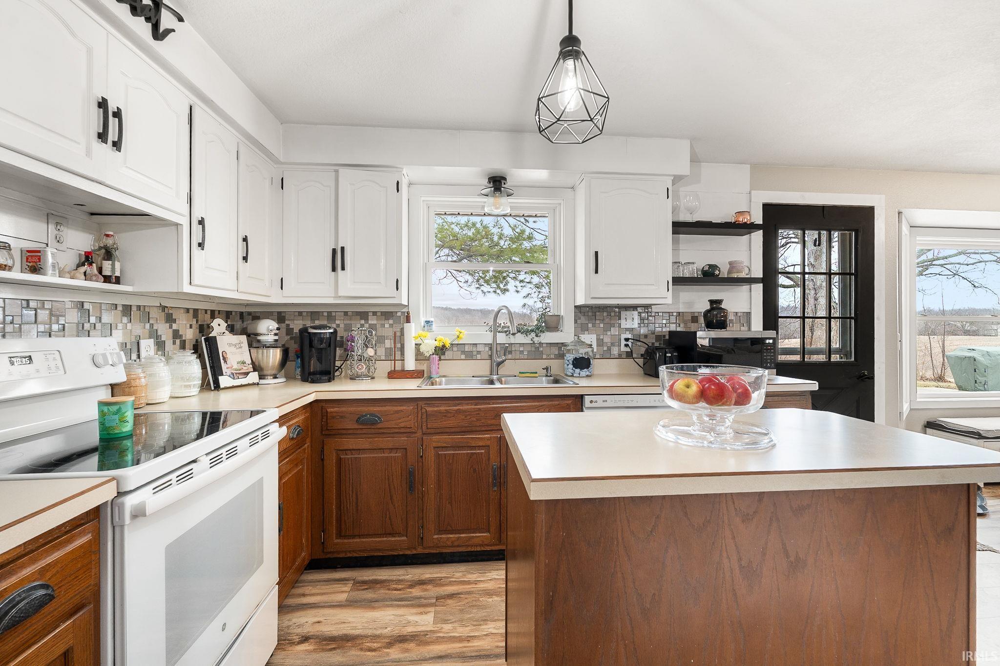 Kitchen with open shelves, white electric range oven, light countertops, a kitchen island, and dual tone cabinetry