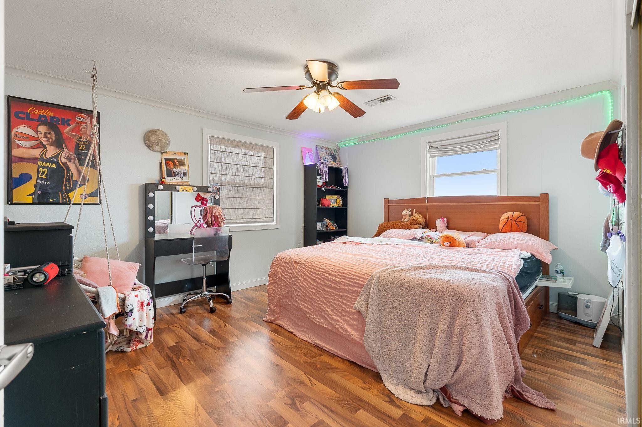 Bedroom featuring wood finished floors, a ceiling fan, and crown molding