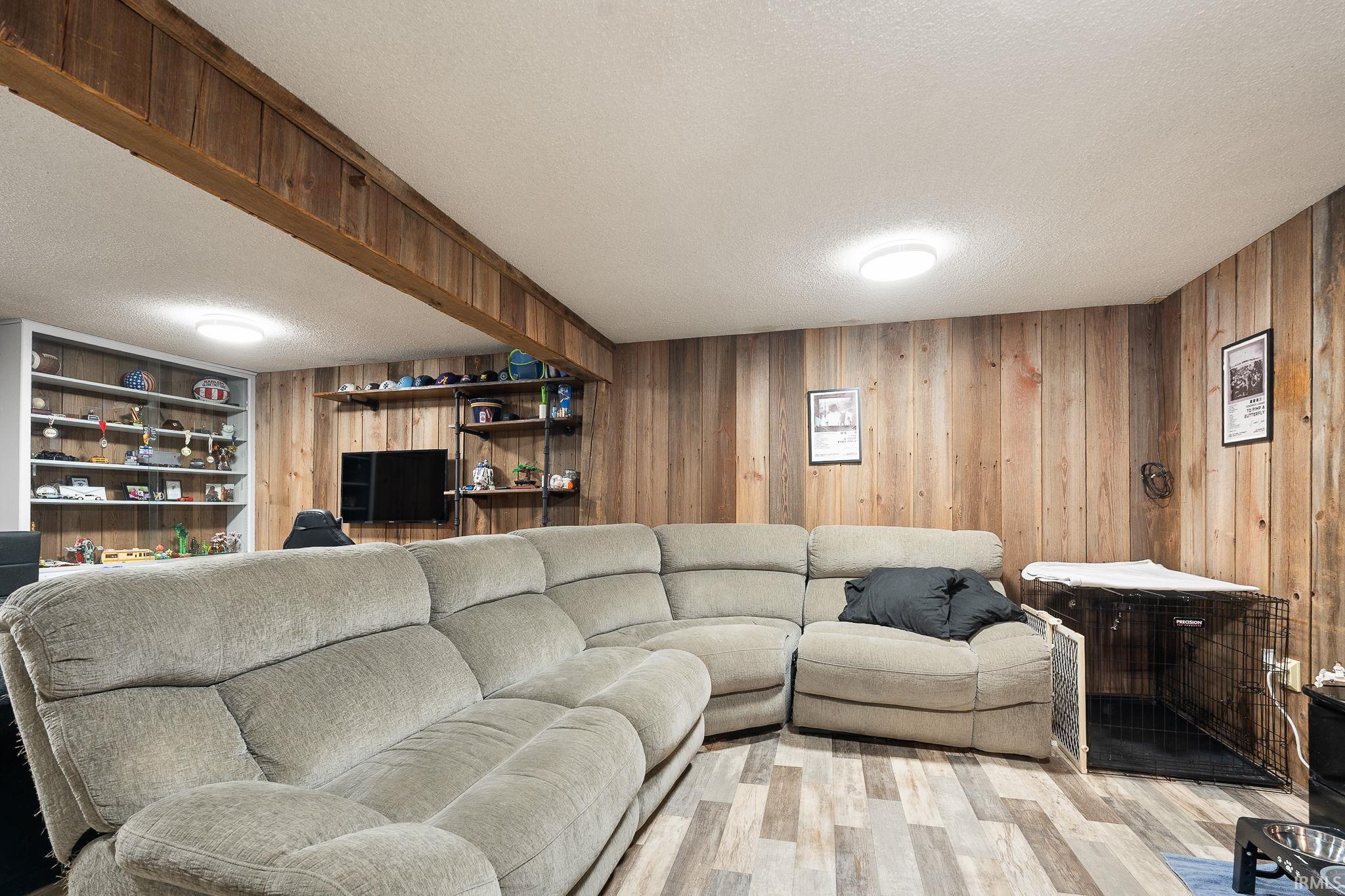 Living area featuring a textured ceiling, wood finished floors, and wood walls
