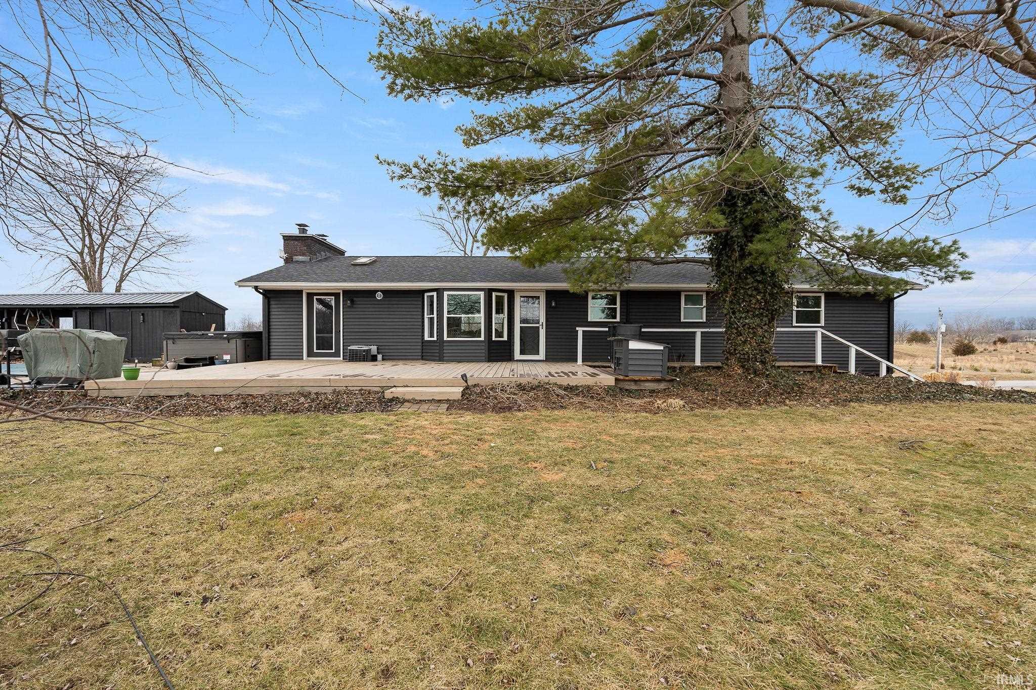 Back of property featuring a chimney, a hot tub, a yard, and a wooden deck