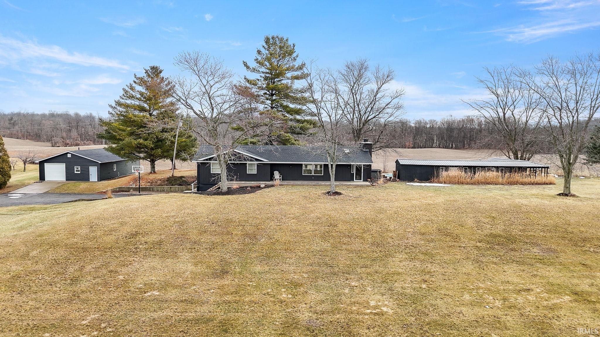View of front of property featuring an outdoor structure, a garage, a front yard, a chimney, and driveway