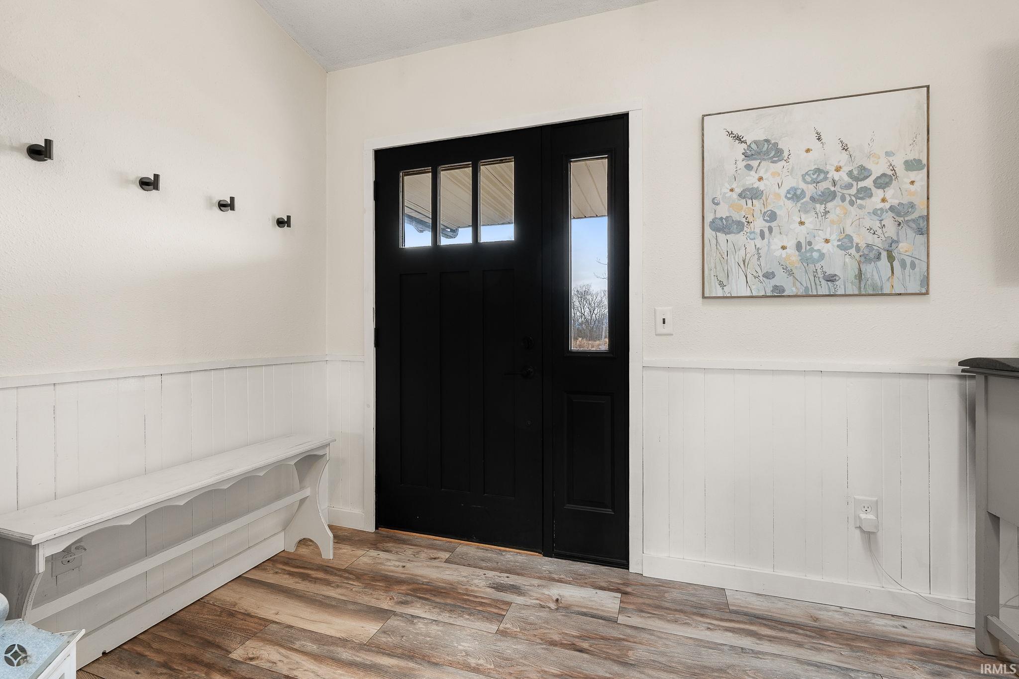 Entrance foyer featuring wood finished floors and wainscoting