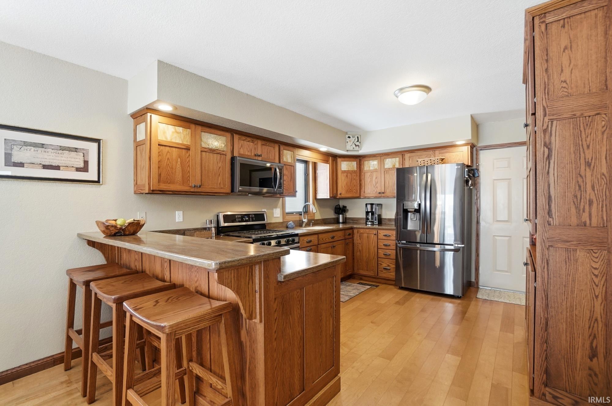 Kitchen with a kitchen breakfast bar, wood finish cabinets, a peninsula, and stainless steel appliances