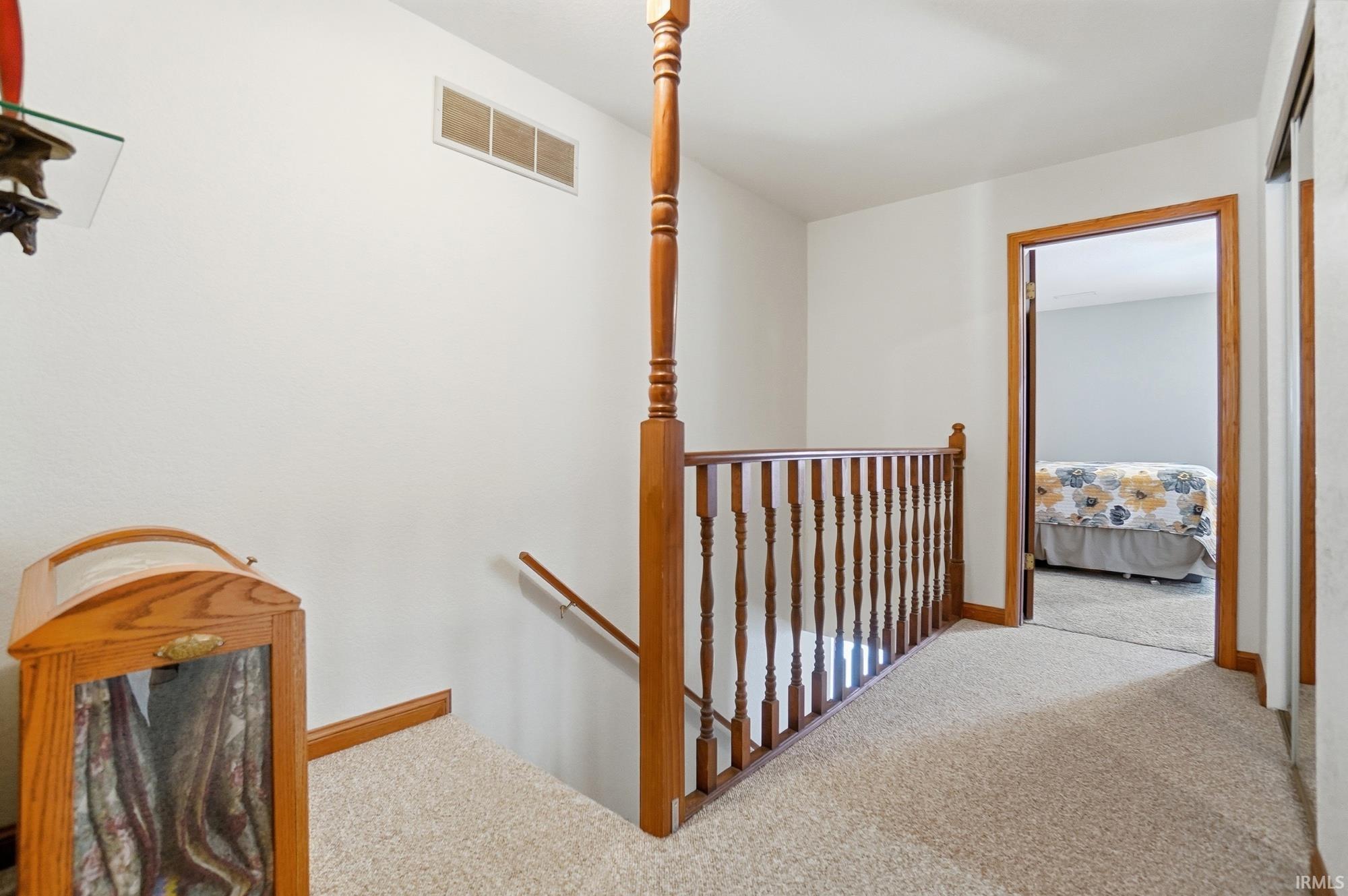Hallway with carpet and an upstairs landing